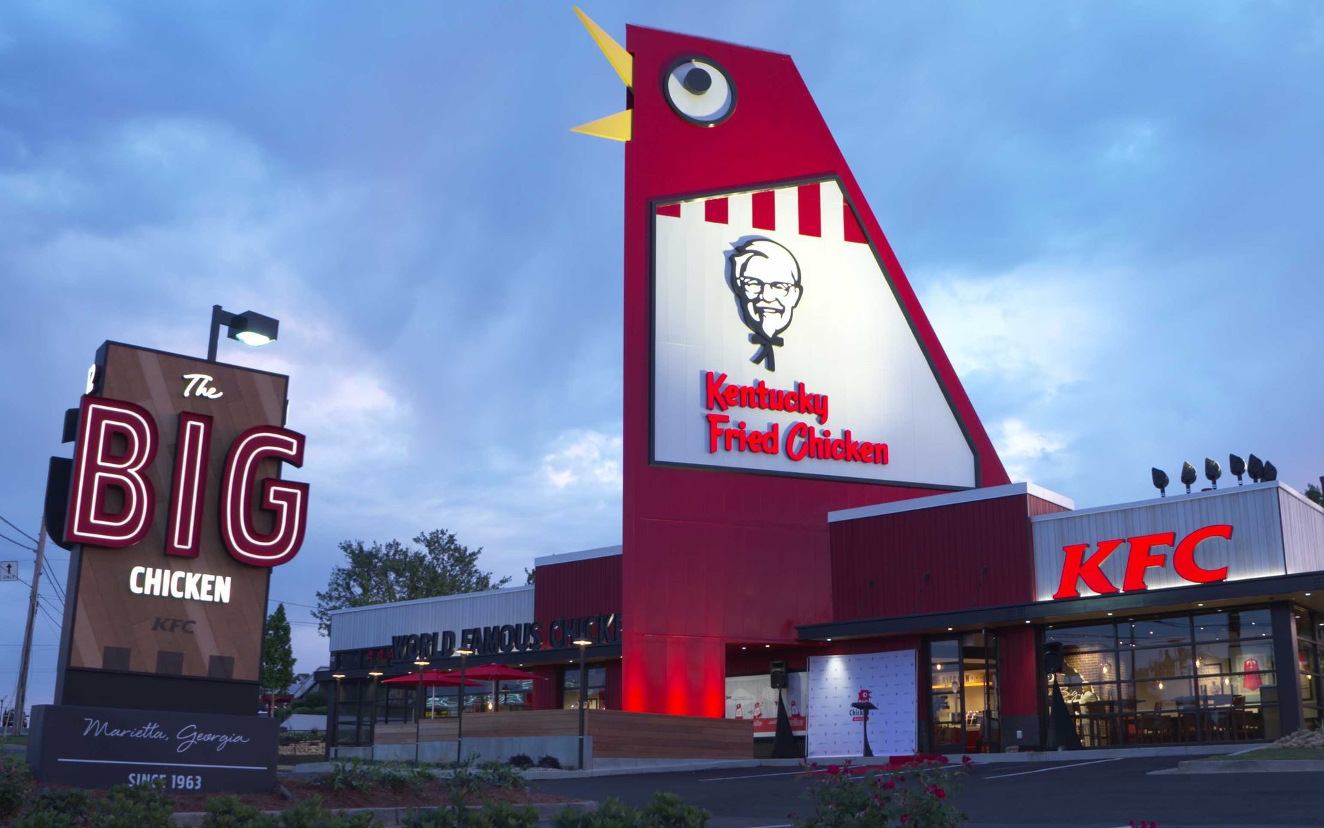 A kfc restaurant with a big chicken sign in front of it