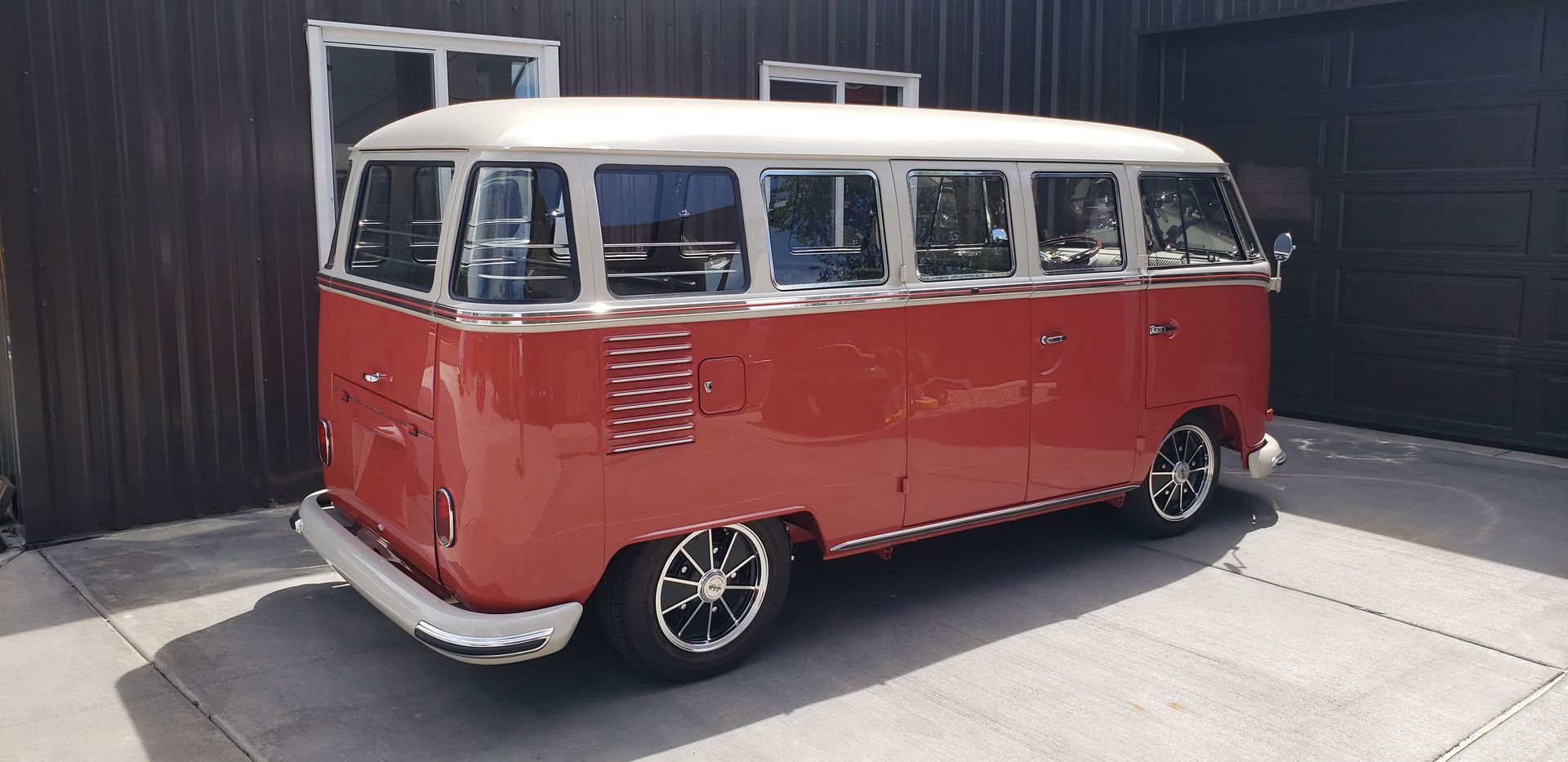 A red bus is parked in a parking lot in front of a building.