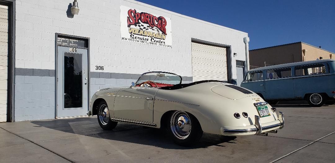 A white car is parked in front of a white building.