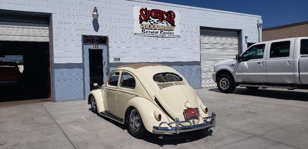 A volkswagen beetle is parked in front of a garage.
