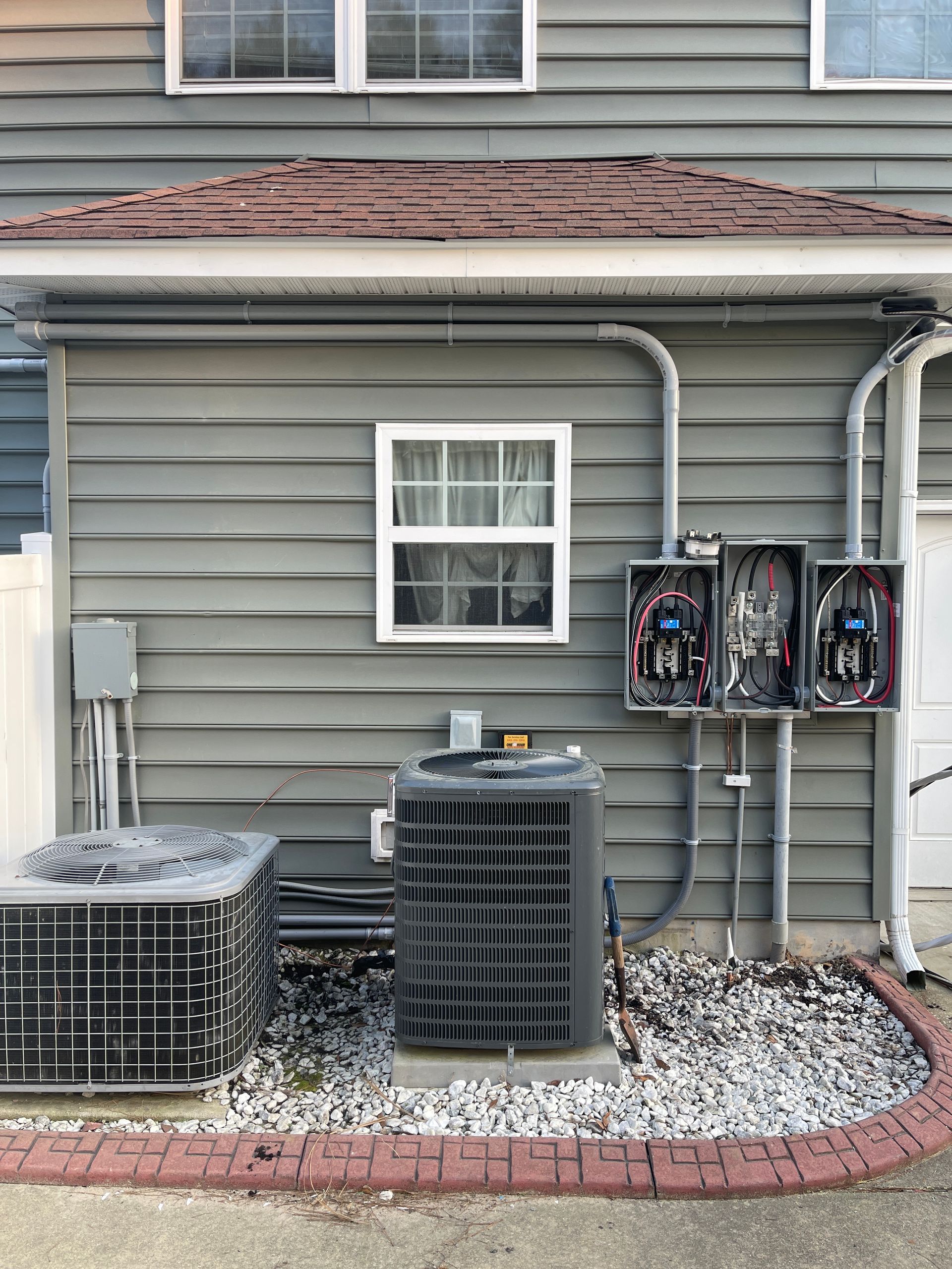 Two electrical panels are installed in a wall next to a window.