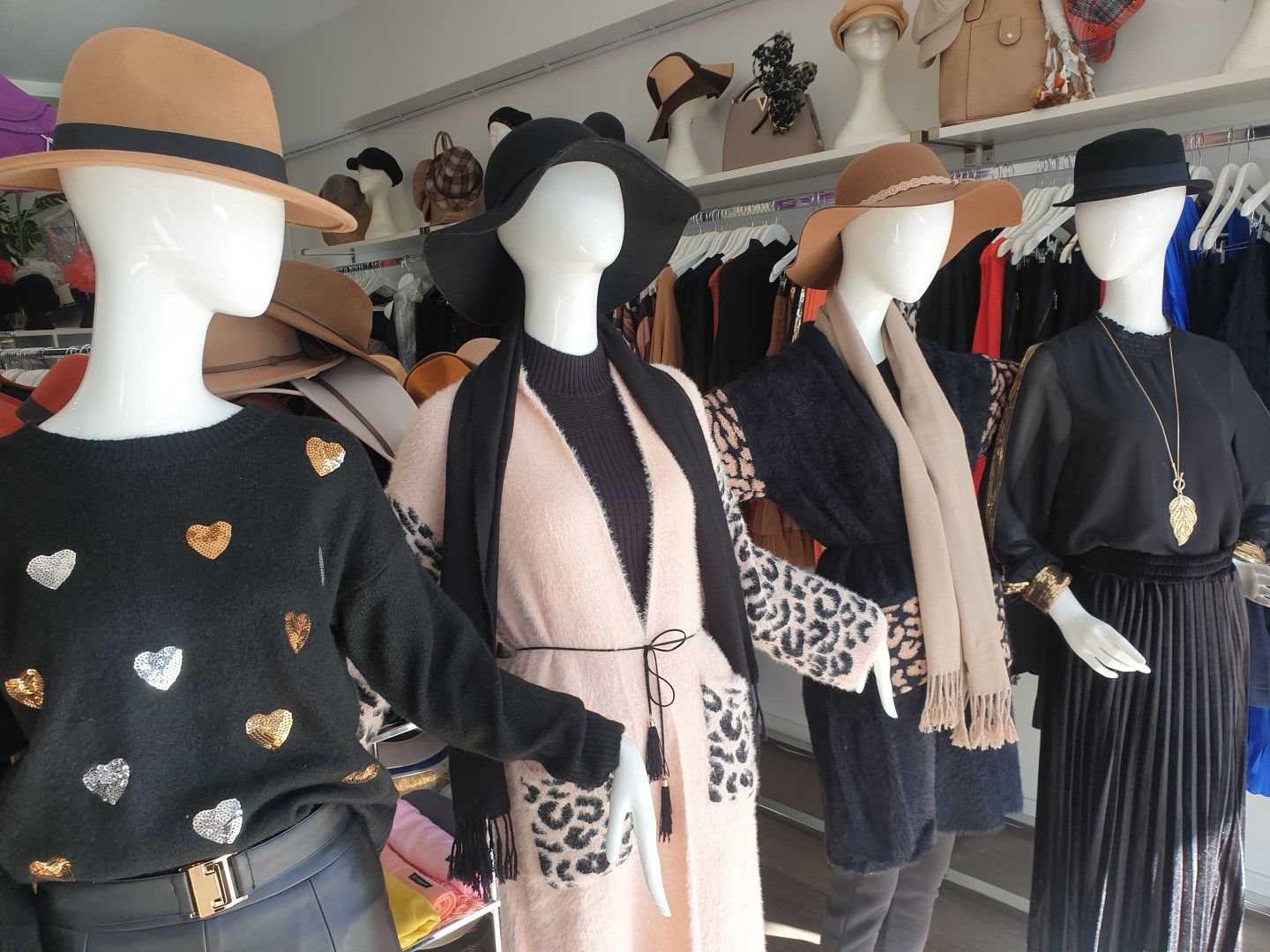 Mannequins in a clothing store display fall and winter fashions: sweaters, scarves, hats.