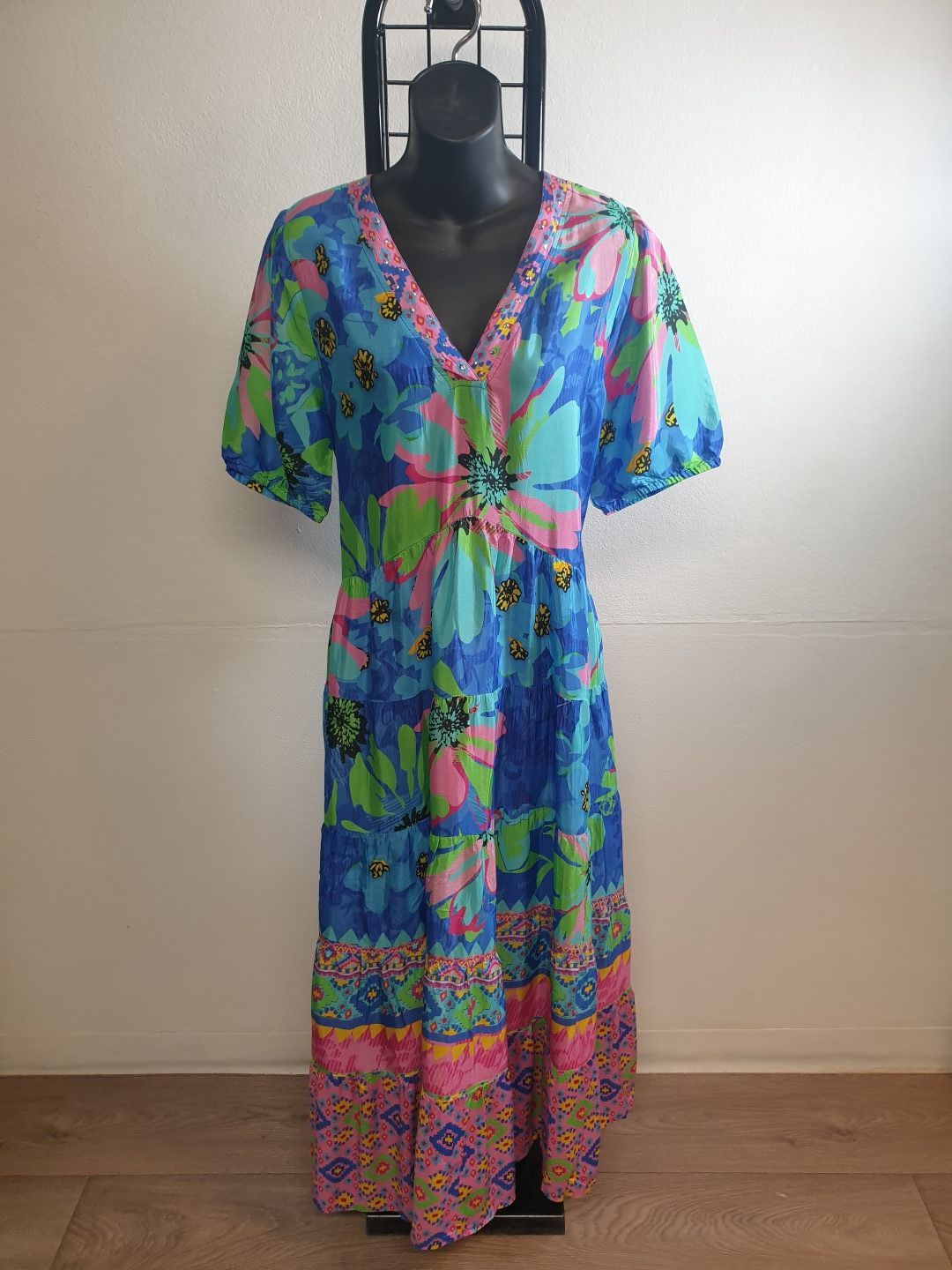 Blue floral maxi dress on a black mannequin, bright colors, V-neck, short sleeves.