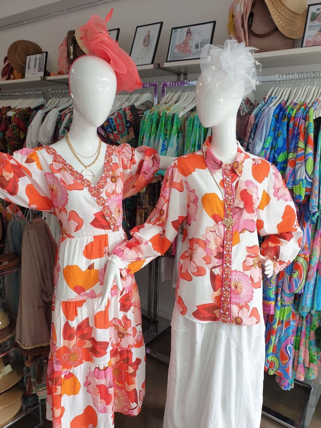 Two mannequins in a boutique, one in a floral dress, the other in a floral top and white skirt.