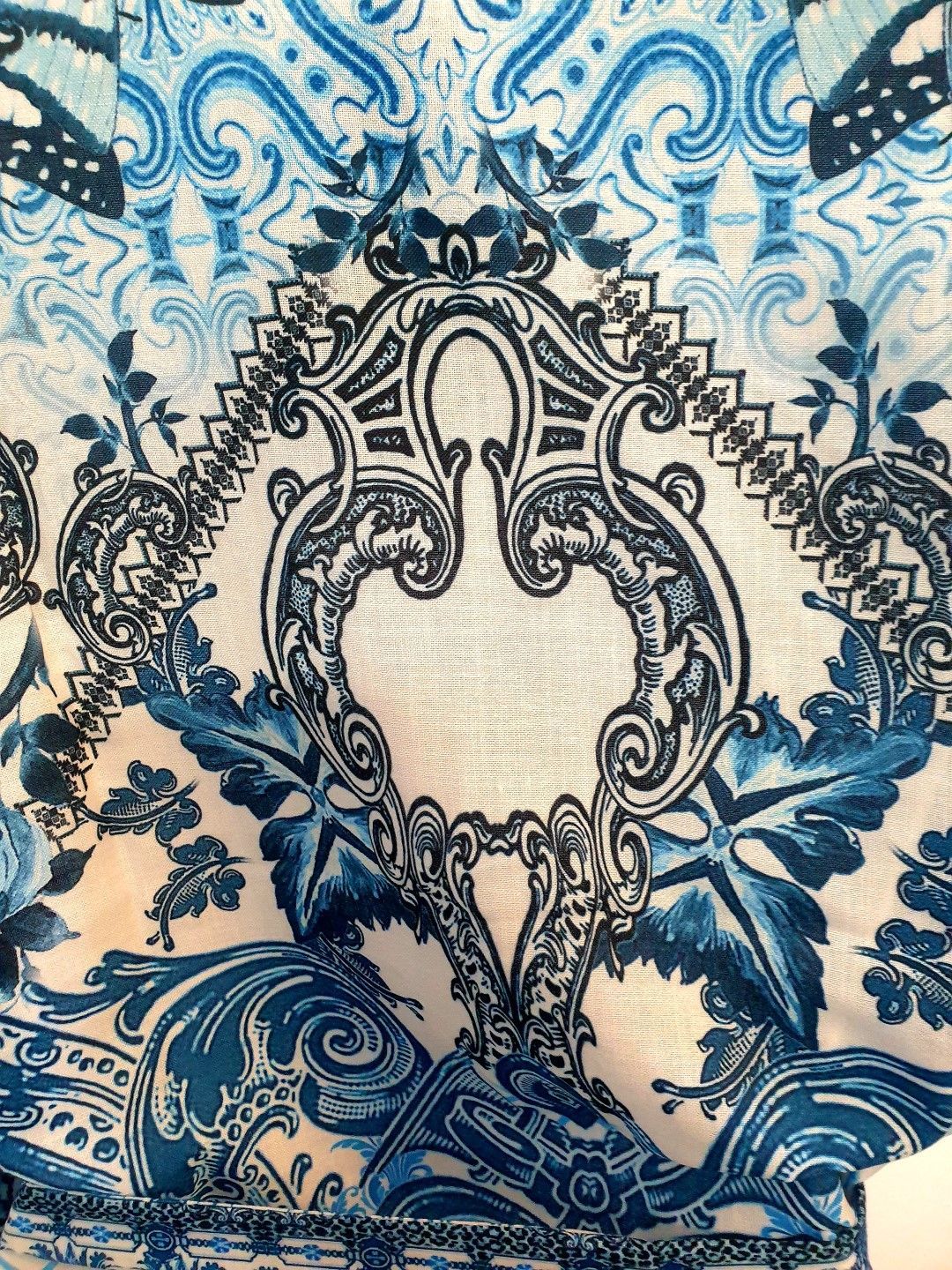 Blue and white baroque-style pattern on fabric. Floral and ornate details.
