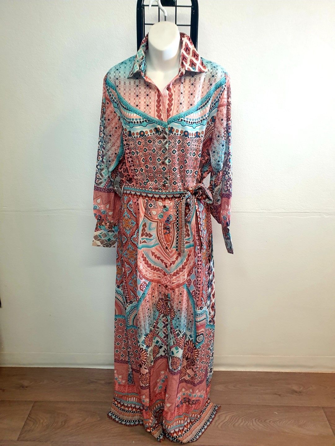 Long, patterned dress on a mannequin; pink, blue, and white floral print with a belt.