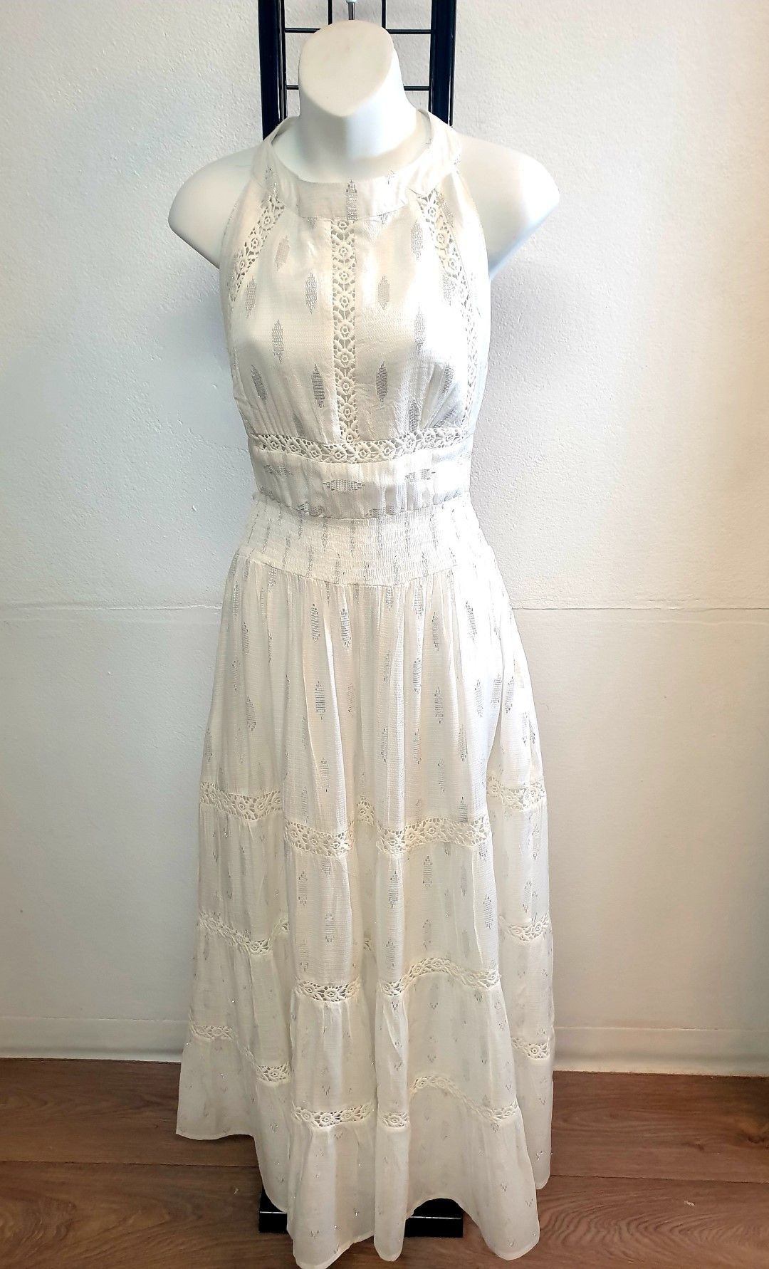 White halter dress on a mannequin, with detailed lacework, displayed indoors.