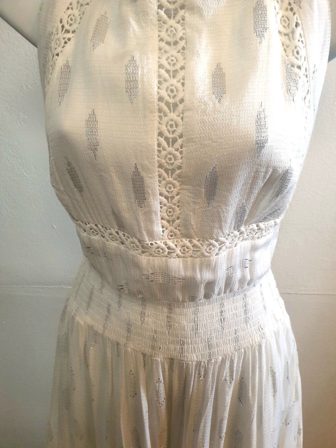White dress with silver accents, lace details on bodice and waist, displayed on a mannequin.