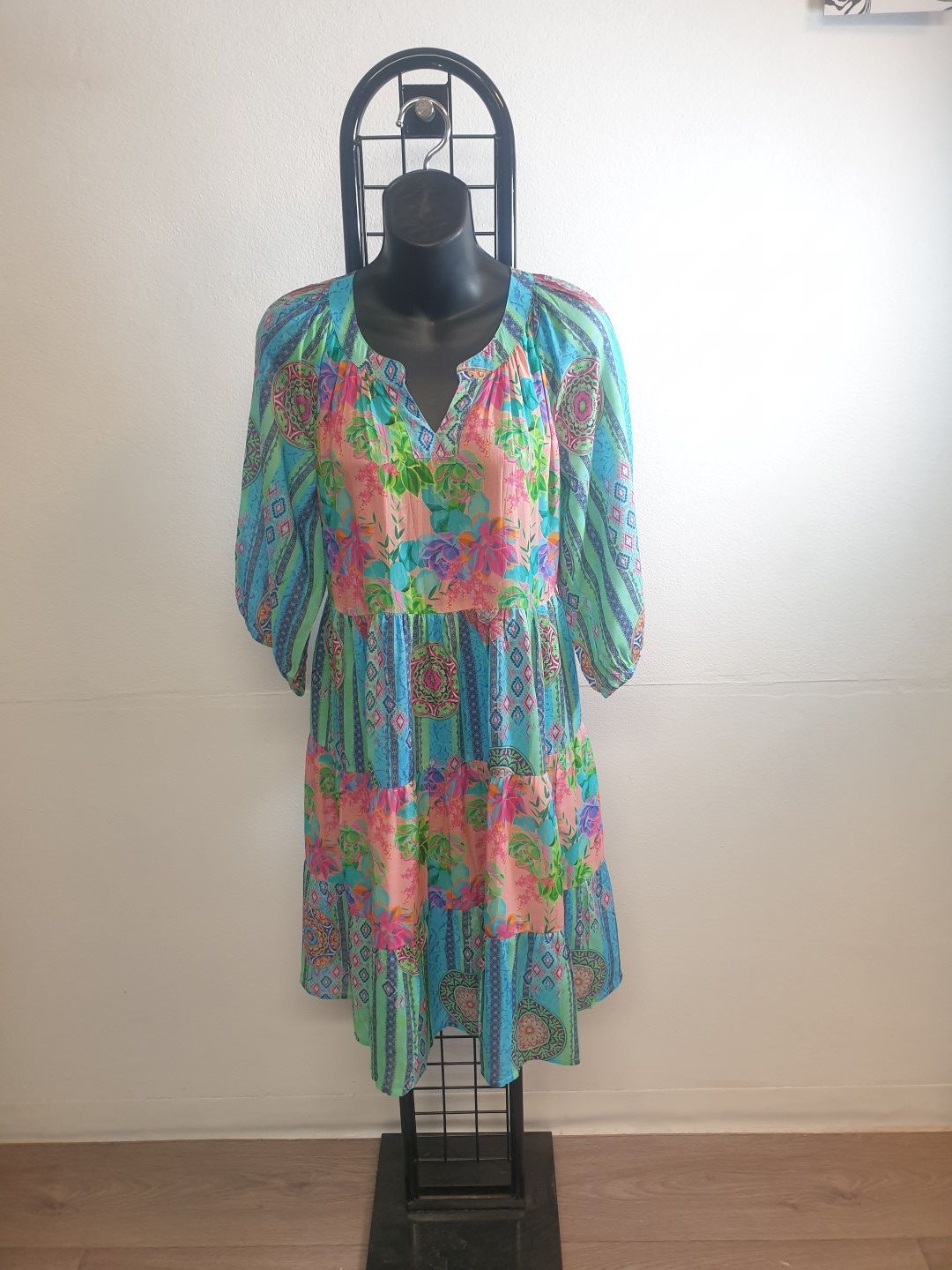 Dress with blue, pink, and green floral and striped patterns on a black mannequin.