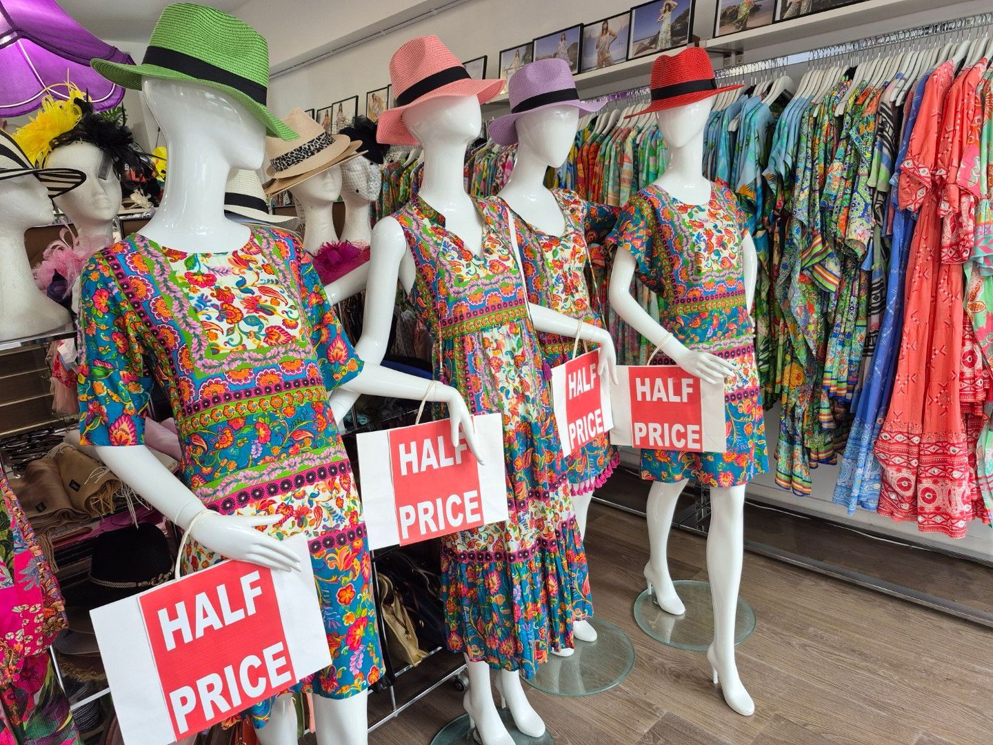 Mannequins in a clothing store wearing colorful dresses and hats, 