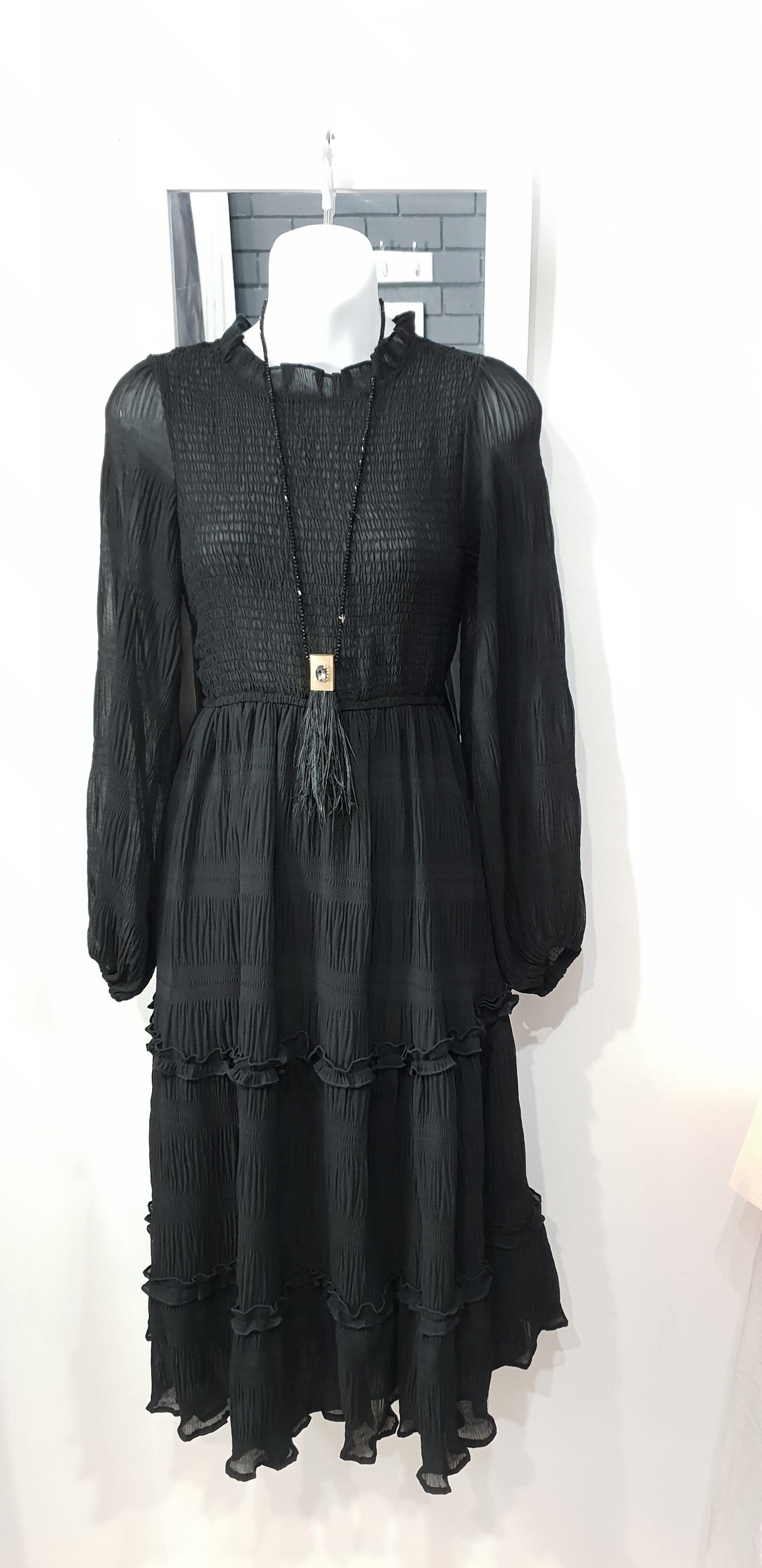 Black long-sleeved midi dress with floral lace detailing hanging on a white mannequin, shot against a white background.