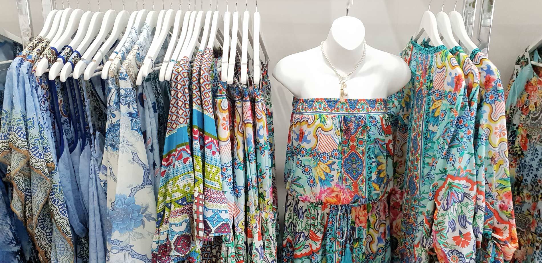 Clothing rack with floral print garments; a mannequin in the center displays a skirt.