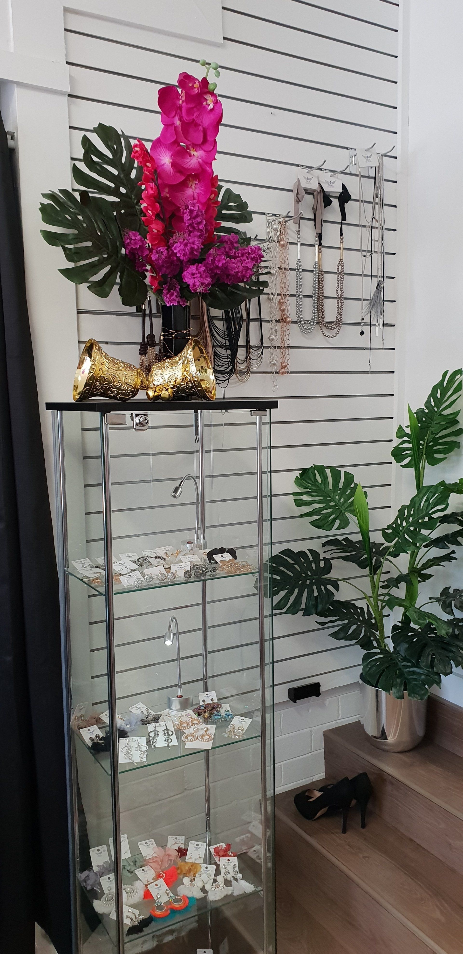 Jewelry display with a glass cabinet, decorative flowers, and plants.
