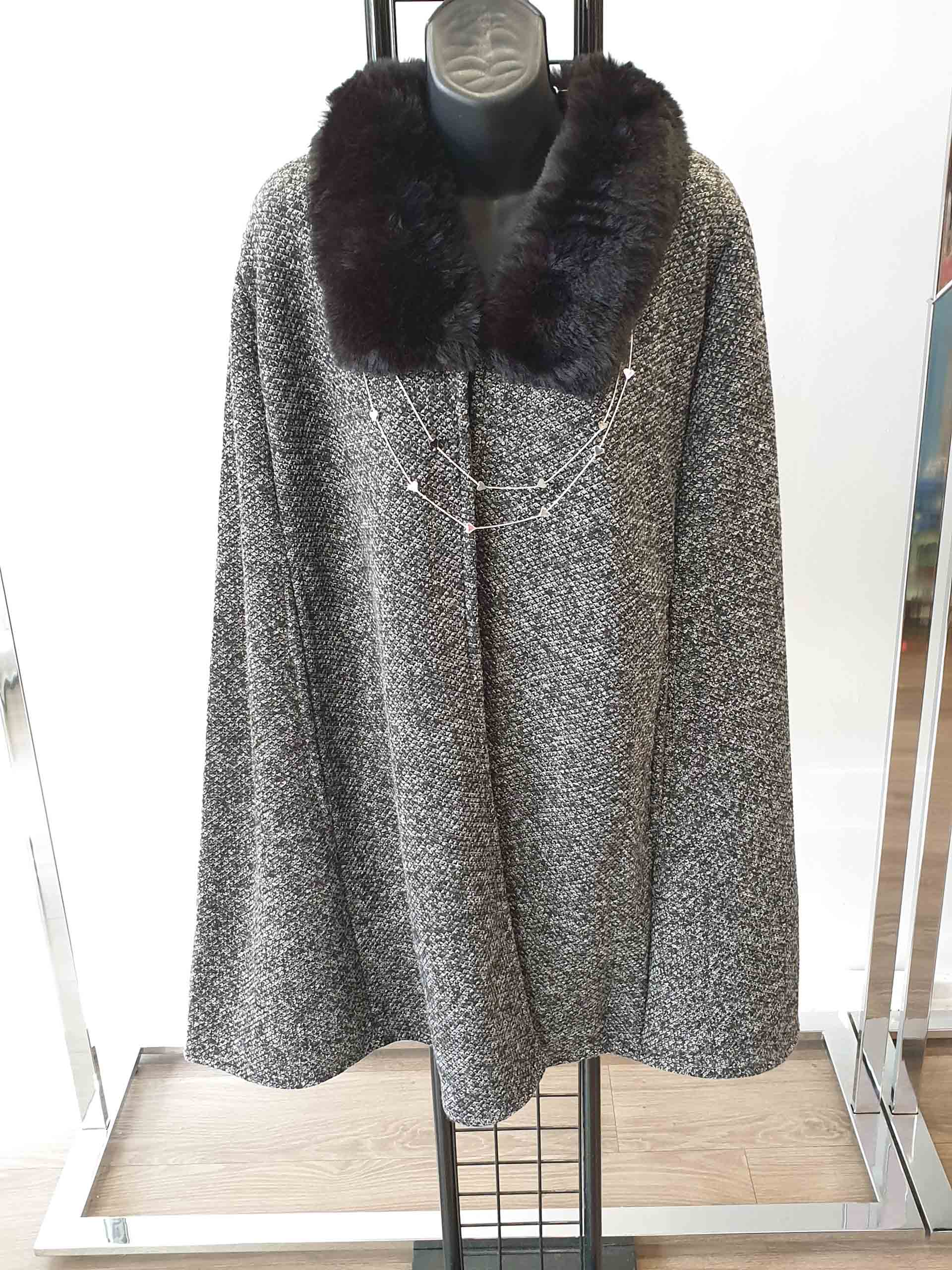 Gray and white patterned cape coat with black fur collar on a black mannequin.