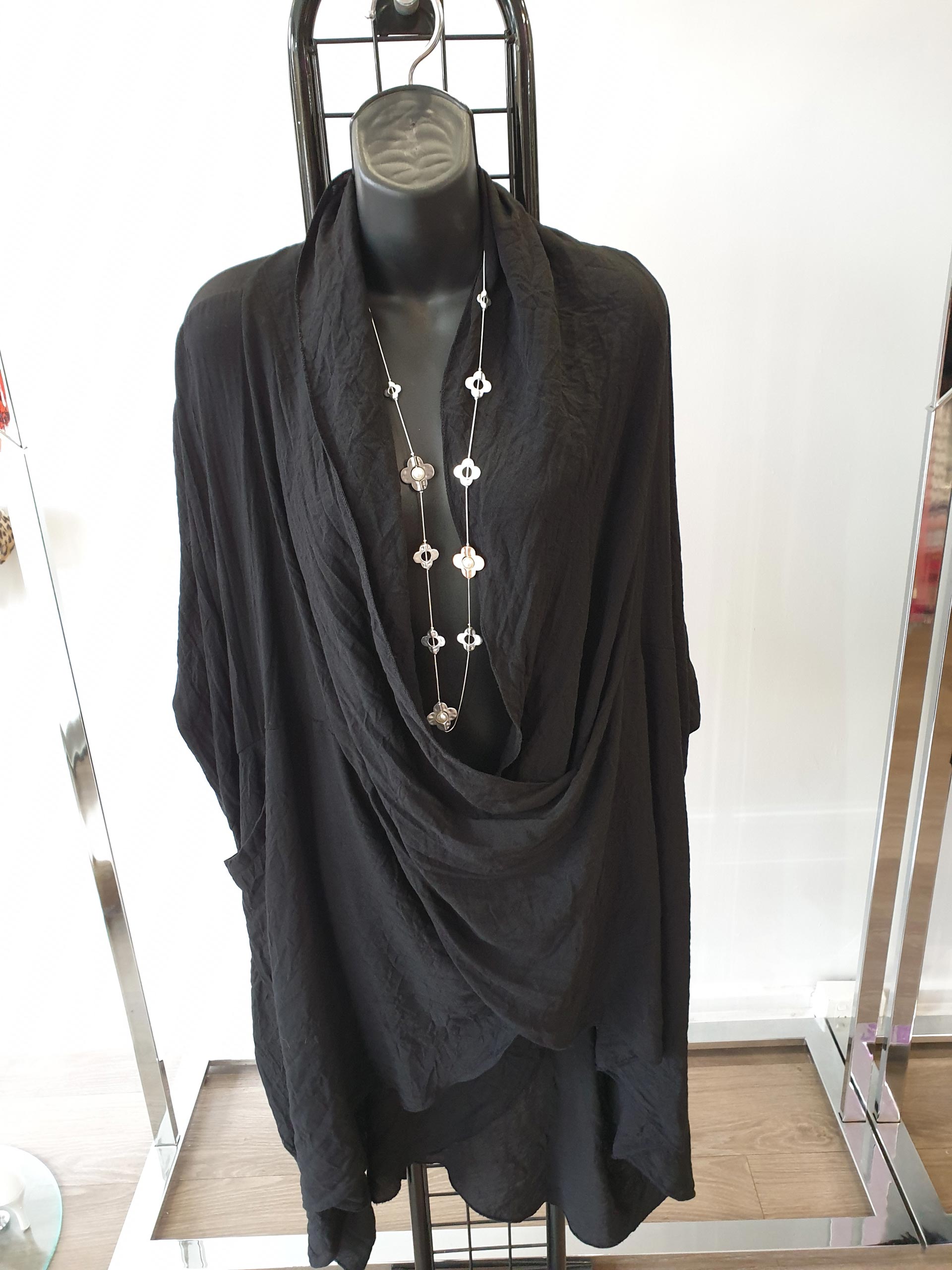Black draped dress on a mannequin with a necklace. The dress is textured and hangs on a rack.