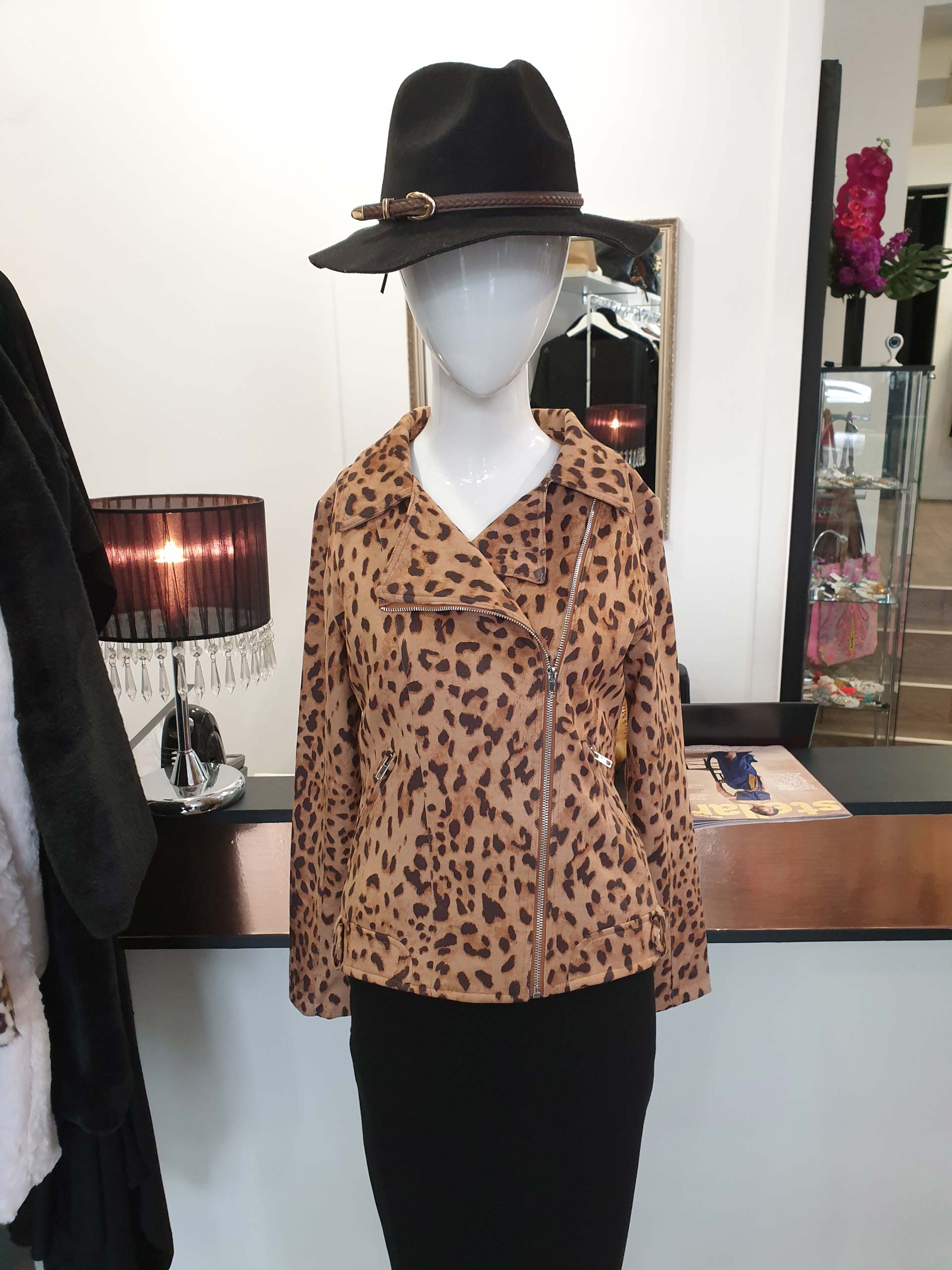 Mannequin in leopard print jacket, black skirt, and hat. Indoors, displayed in a boutique.