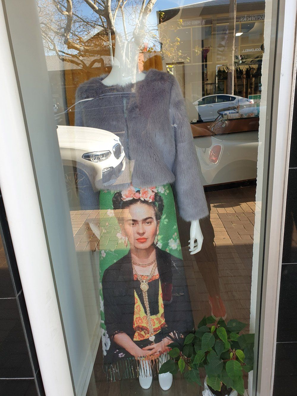 Mannequin in window wearing gray jacket, Frida Kahlo print skirt.