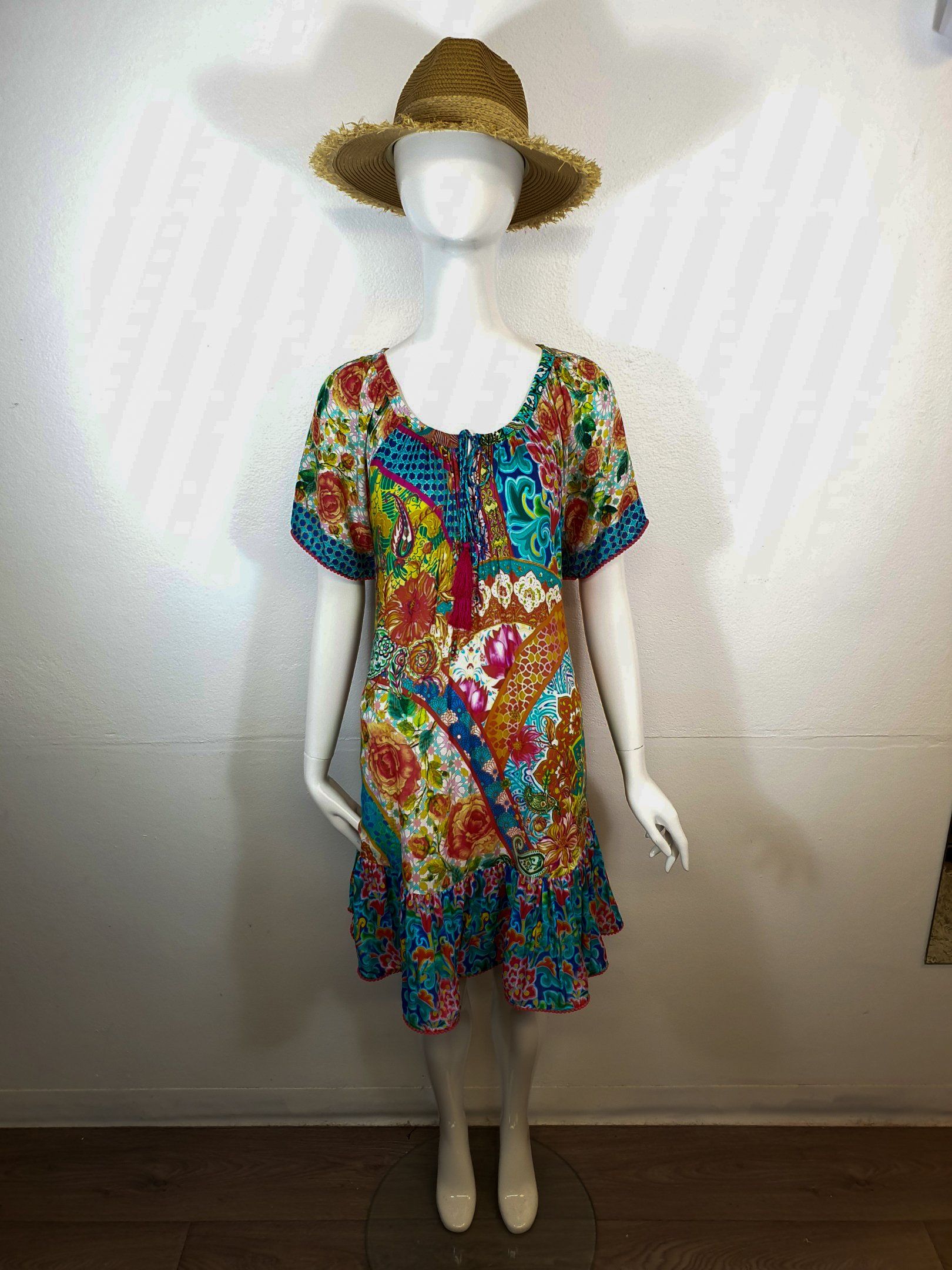 Mannequin wearing a colorful floral print dress and straw hat.