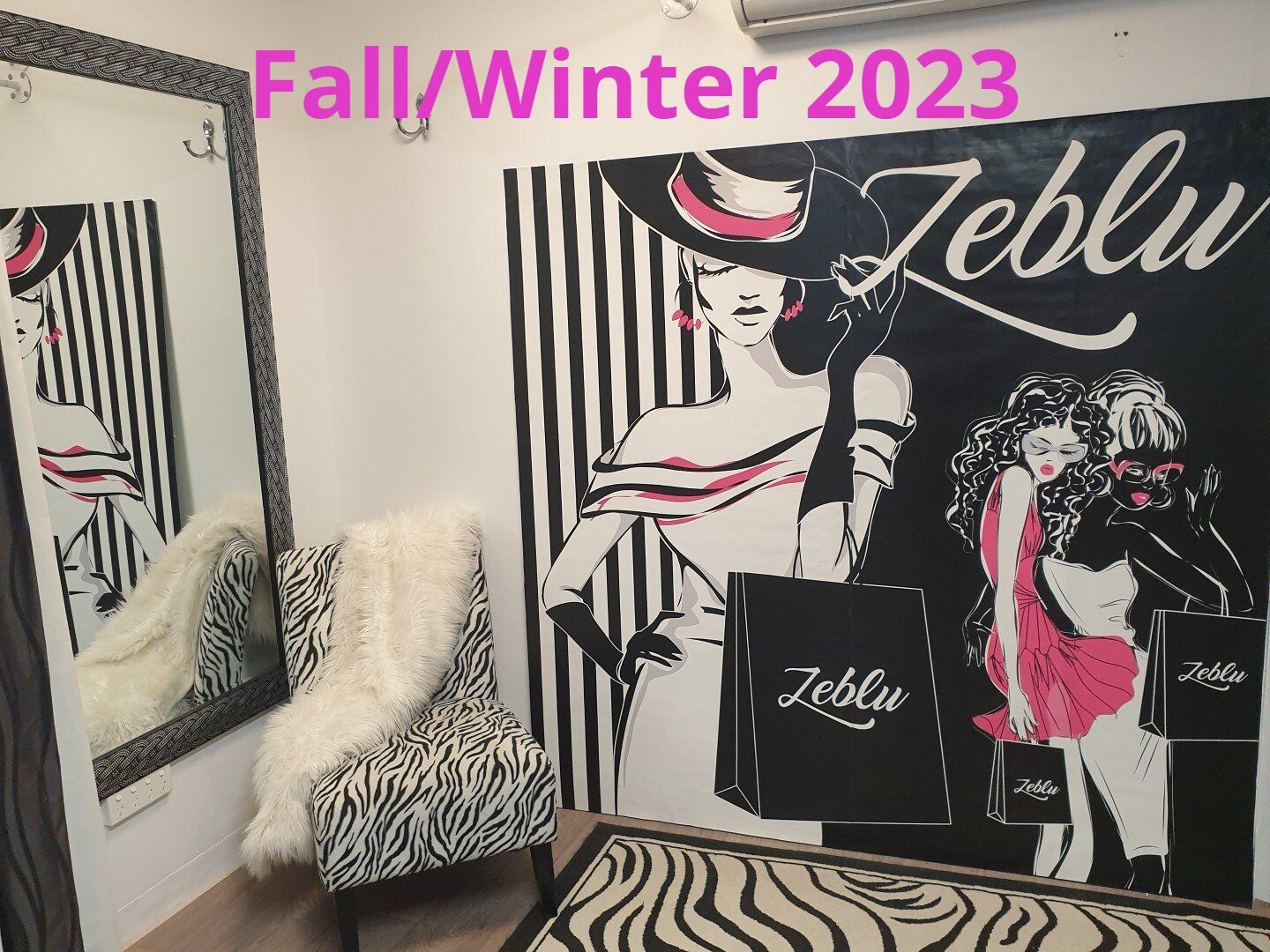 Zebra-print chair and bench, black and white striped wall, Zeblu artwork, mirror, and a fluffy white throw. Fall/Winter 2023 in pink text.