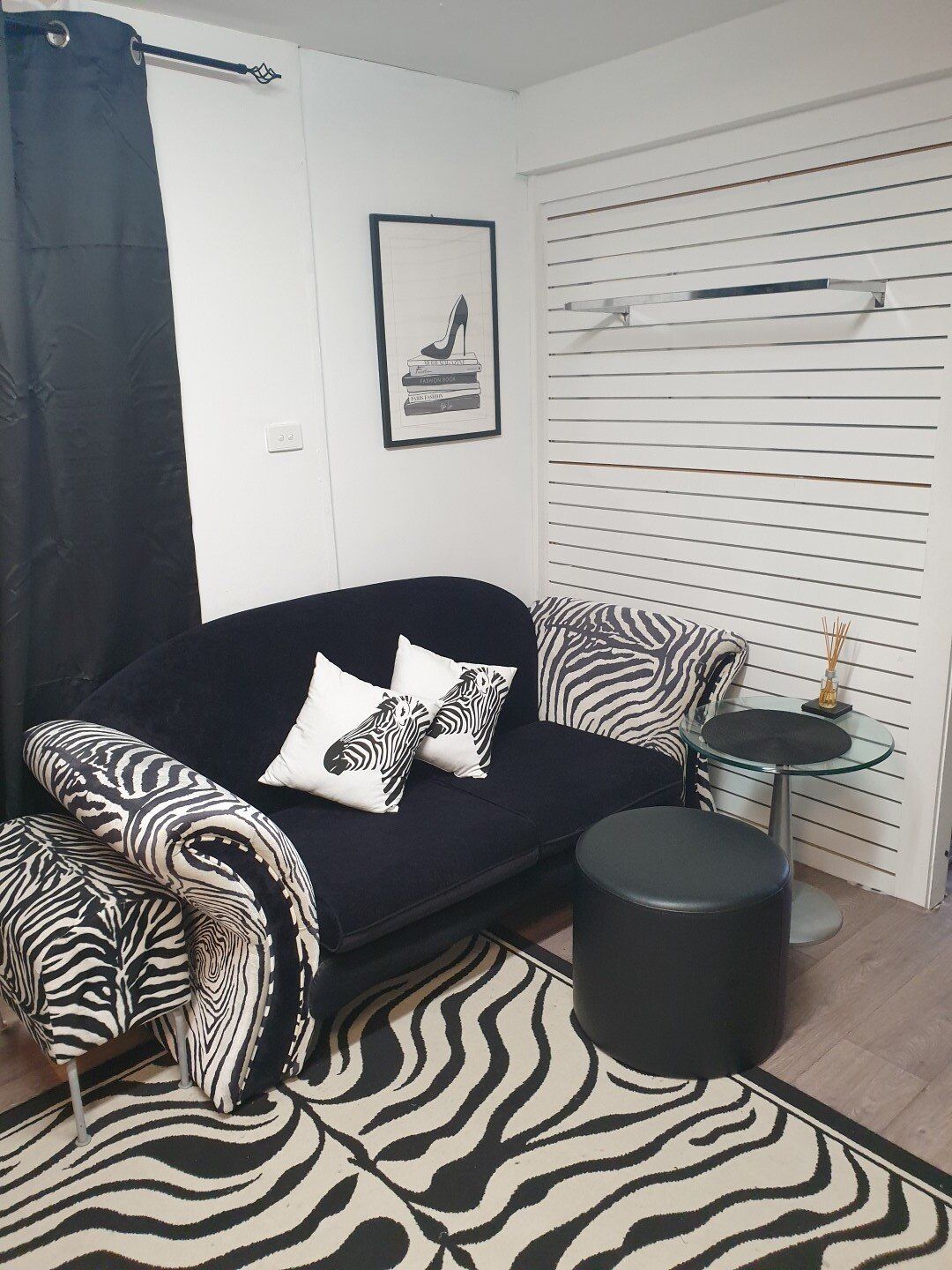 Black and white zebra-themed sitting area. Black sofa with zebra cushions, rug, and accent chair.