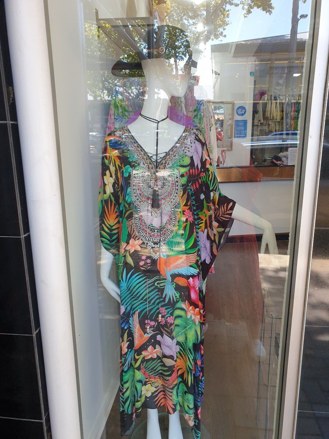 A long, colorful patterned dress on a mannequin in a shop window.