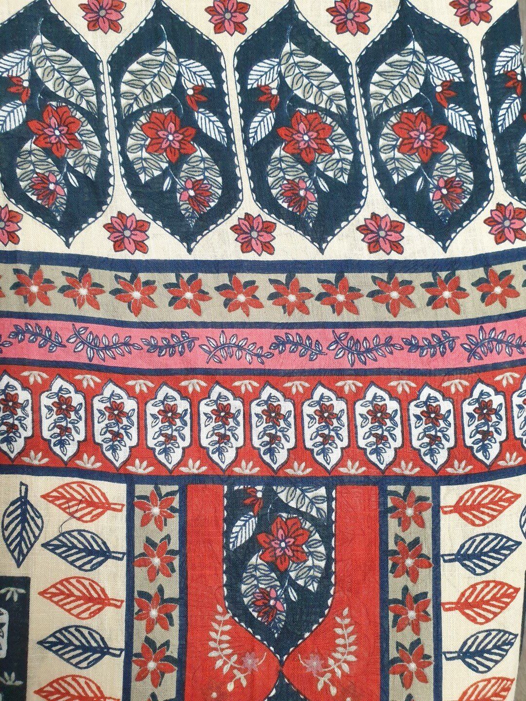 Floral textile with blue, red, pink, and cream colors. Features repeating patterns of leaves and flowers.