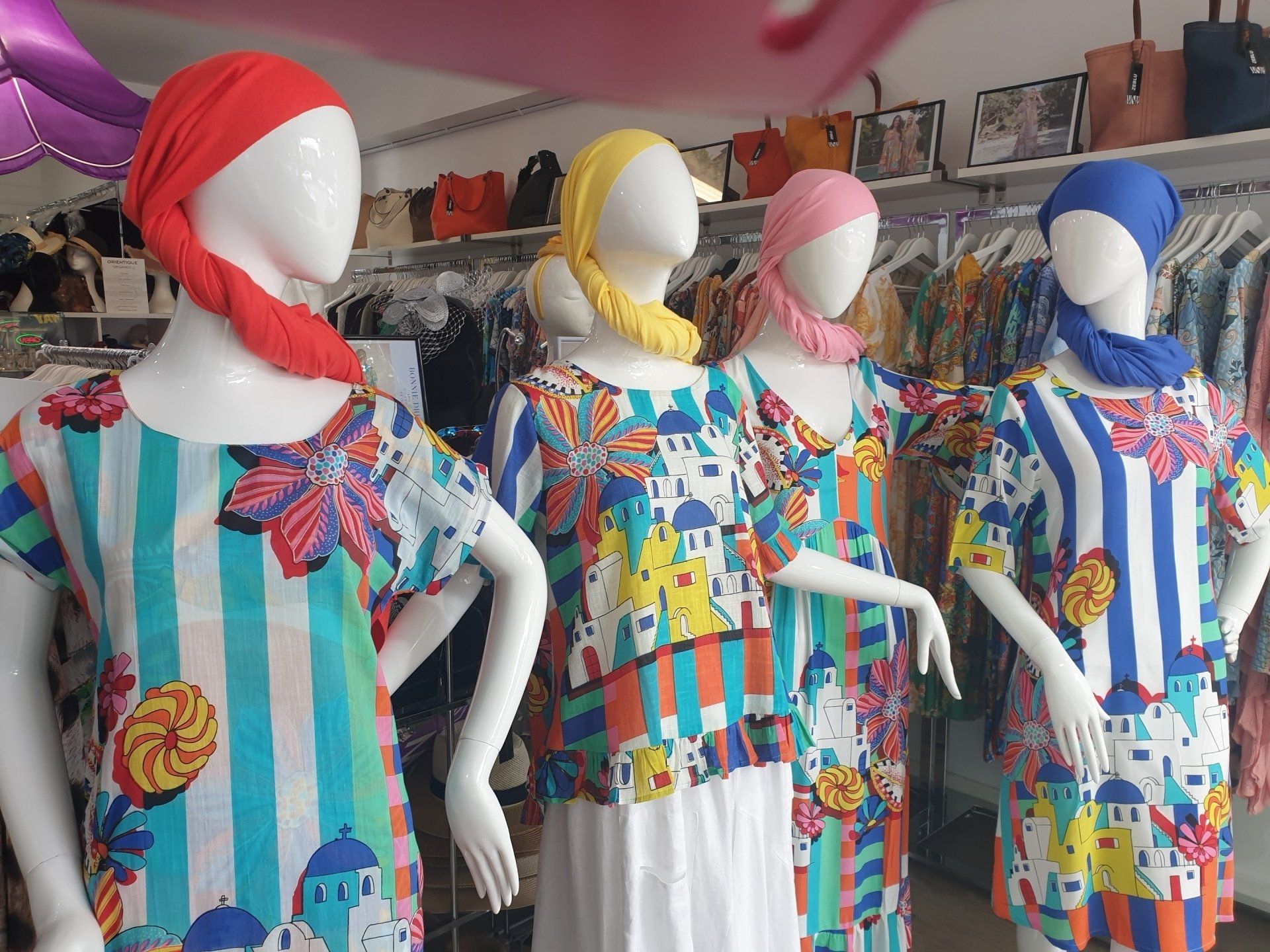 Four mannequins in patterned dresses and headscarves, in a clothing store setting.