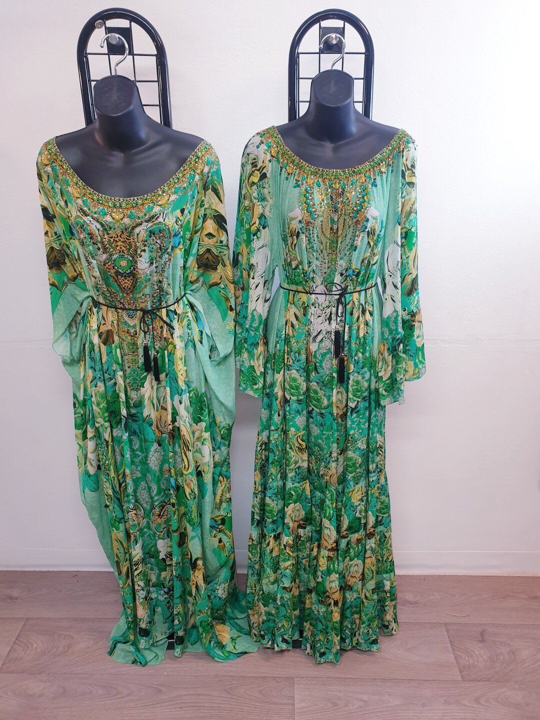 Two green floral maxi dresses on mannequins.
