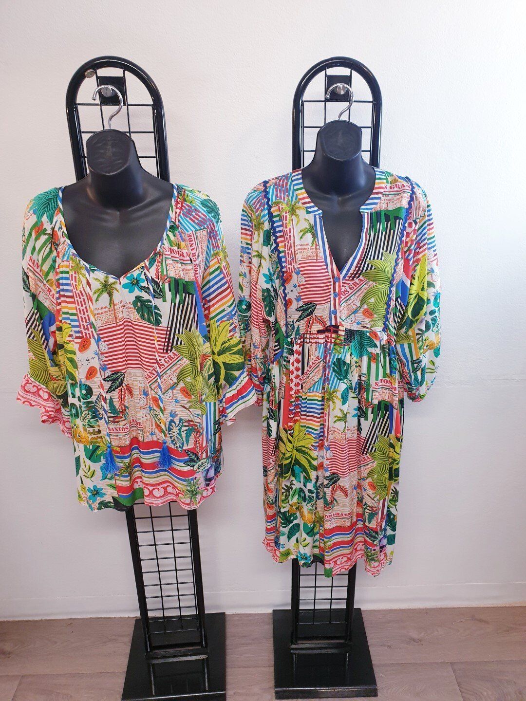 Two floral print tunics on black mannequins.