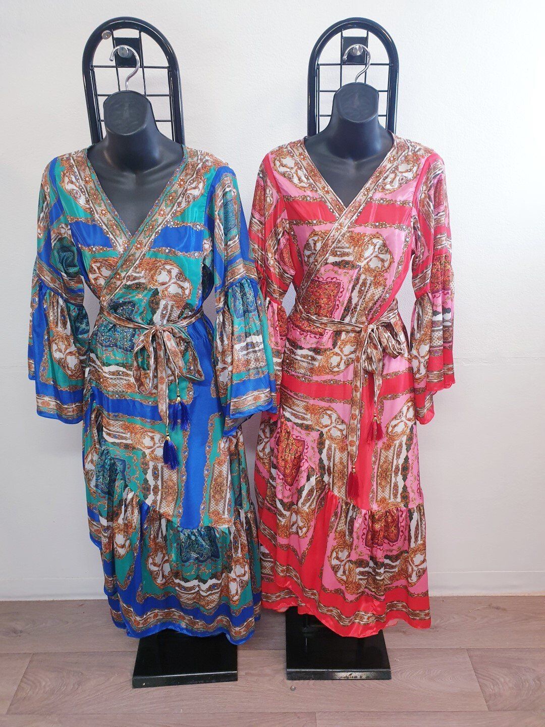 Two patterned wrap dresses on mannequins: one blue, one red.