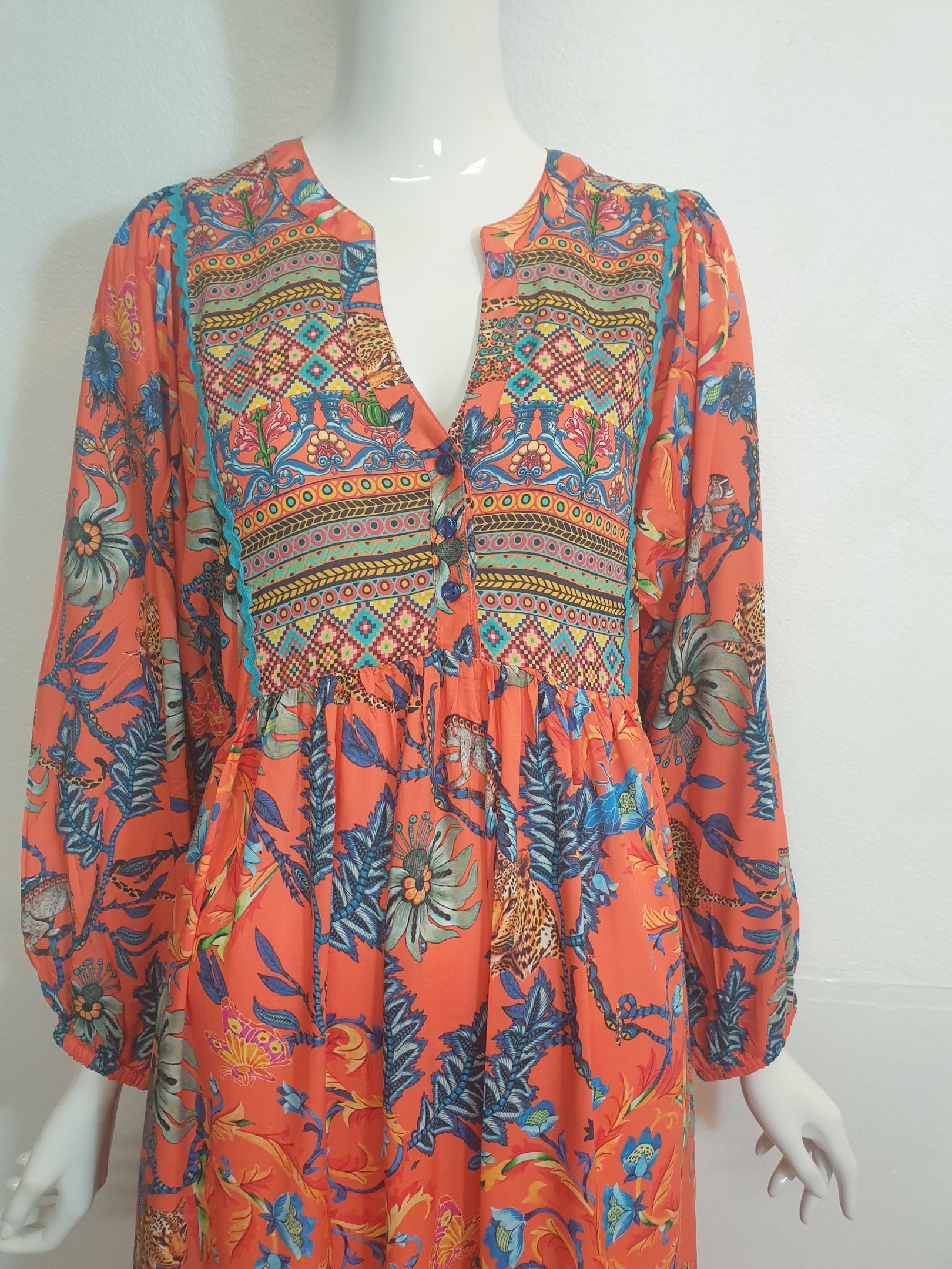 Orange dress with floral print and long sleeves on a mannequin.