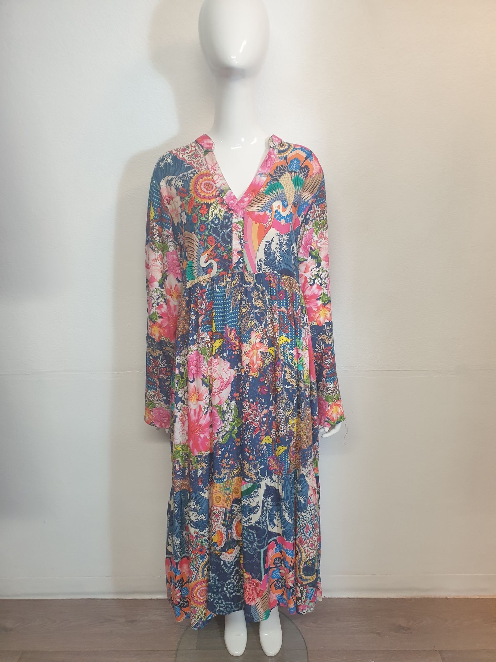 Mannequin wearing a long, floral-print dress with long sleeves. The dress is mainly blue with pink and orange flowers.