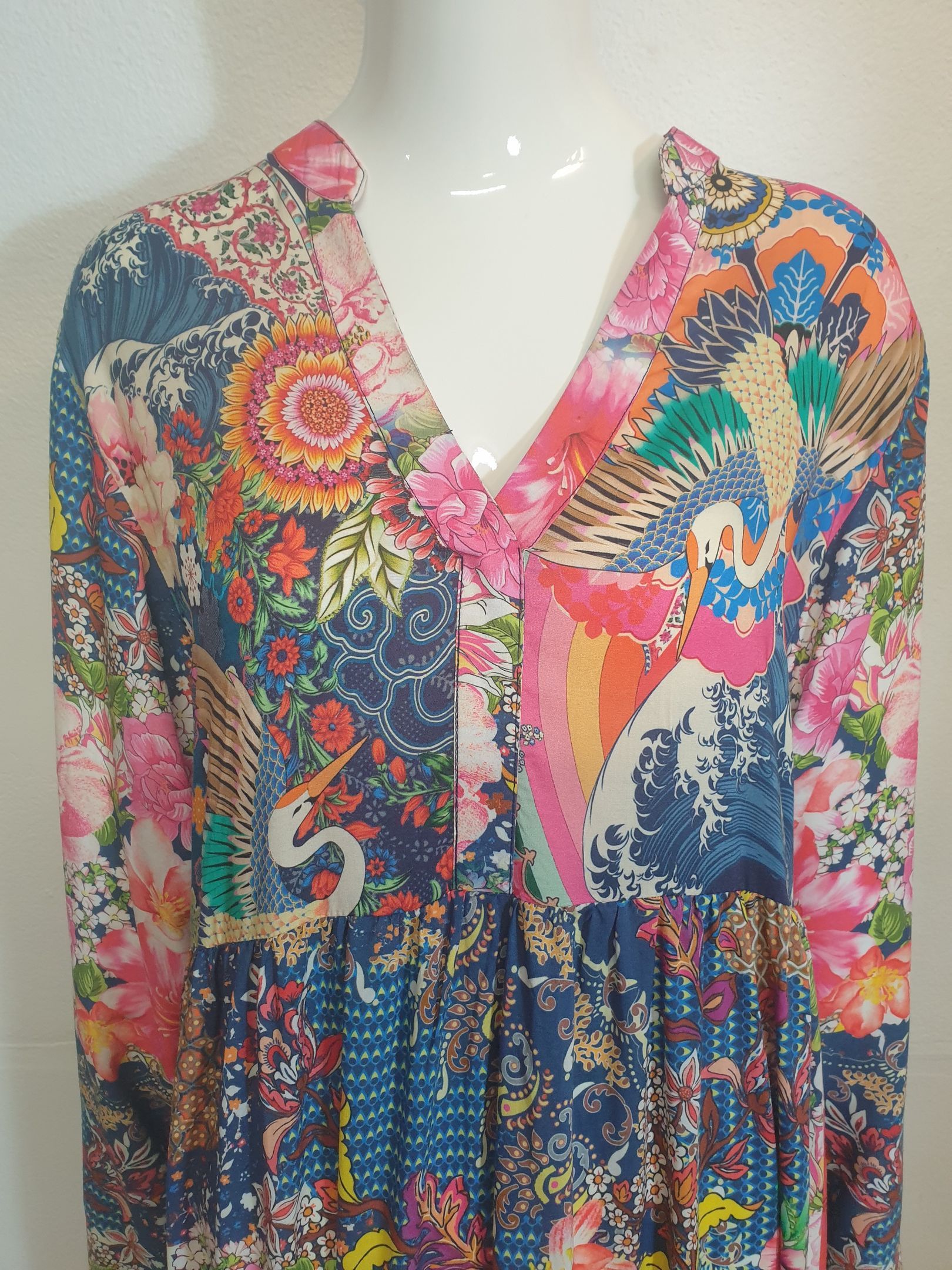Woman's colorful, long-sleeved dress with a V-neck. It features a floral, bird-themed pattern in blue, pink, and orange.