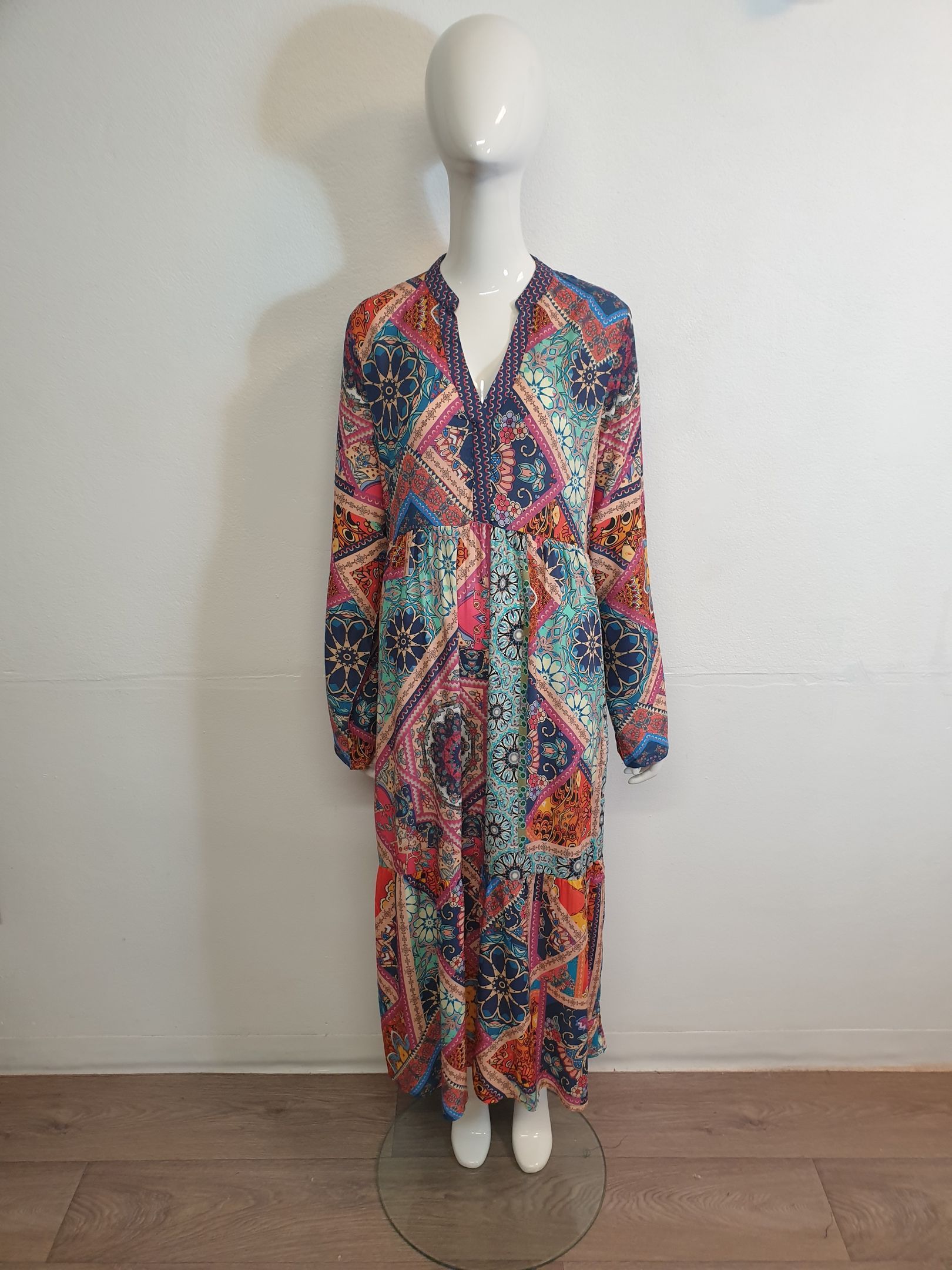 A patterned, flowing maxi dress on a mannequin, with a vibrant mix of colors.