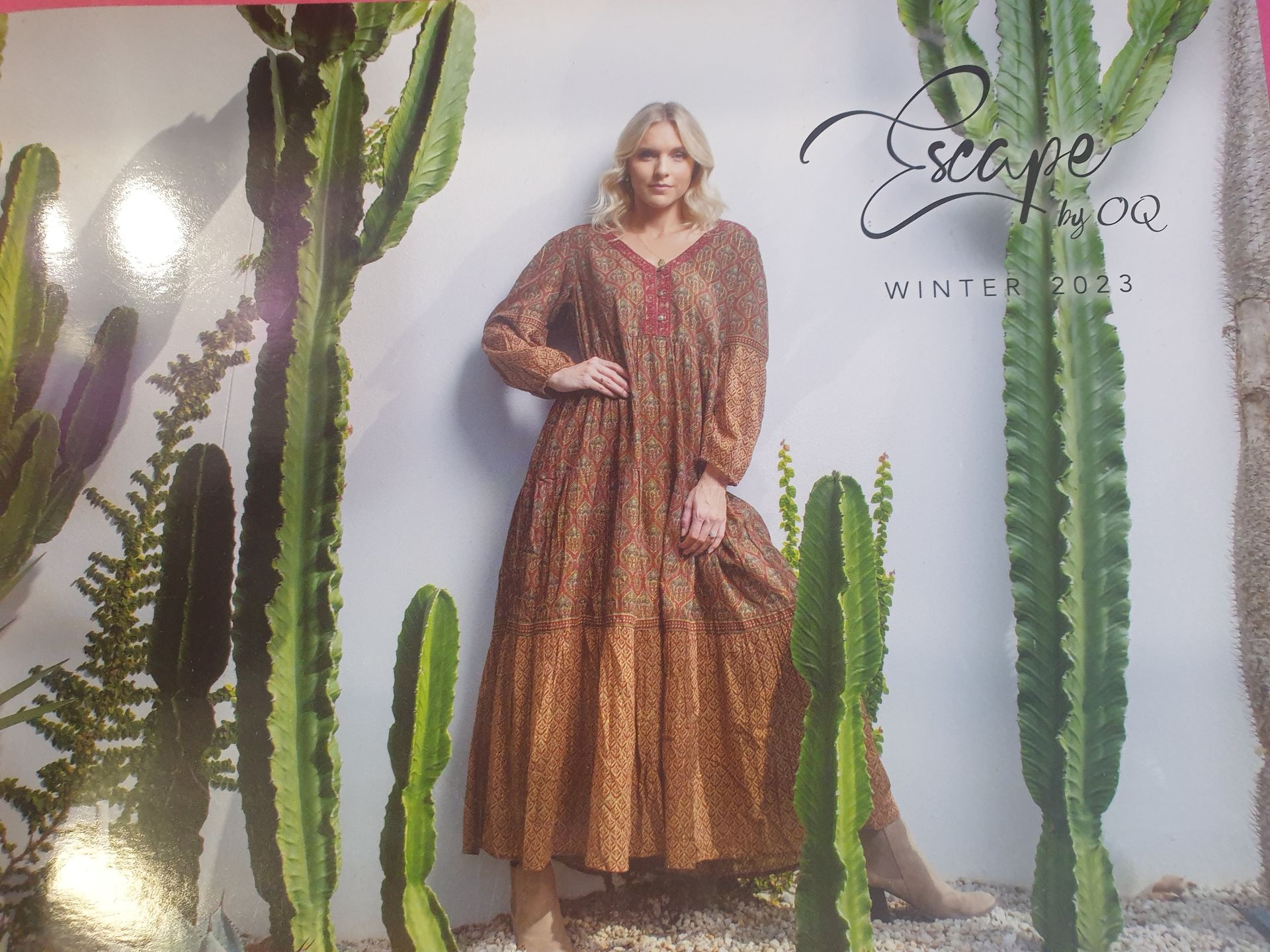 Woman in a patterned dress poses among cacti. 