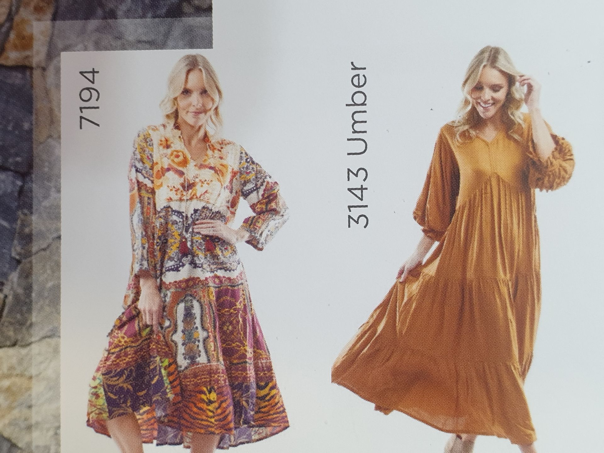 Woman wearing a patterned dress and woman in a long mustard dress; both smiling.