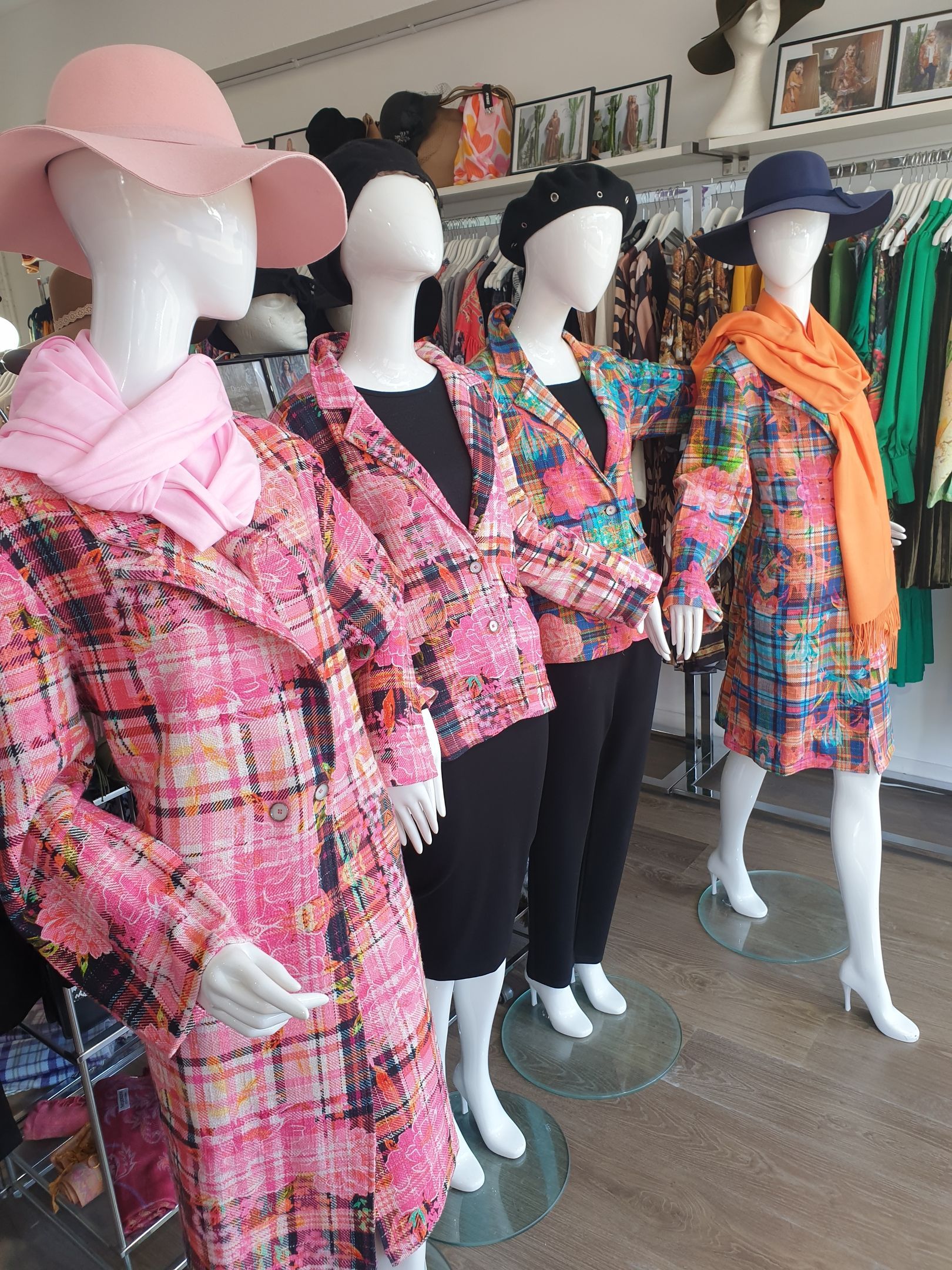 Mannequins in a clothing store showcase colorful coats and hats.