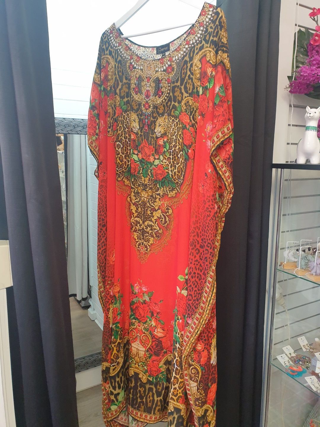 Red patterned kaftan dress hanging on a white hanger.