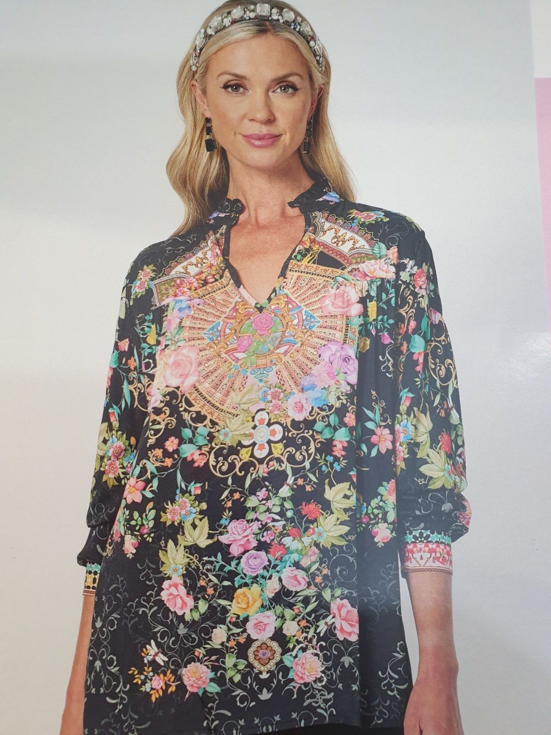 Woman in black floral tunic with colorful embellishment and beaded headband.