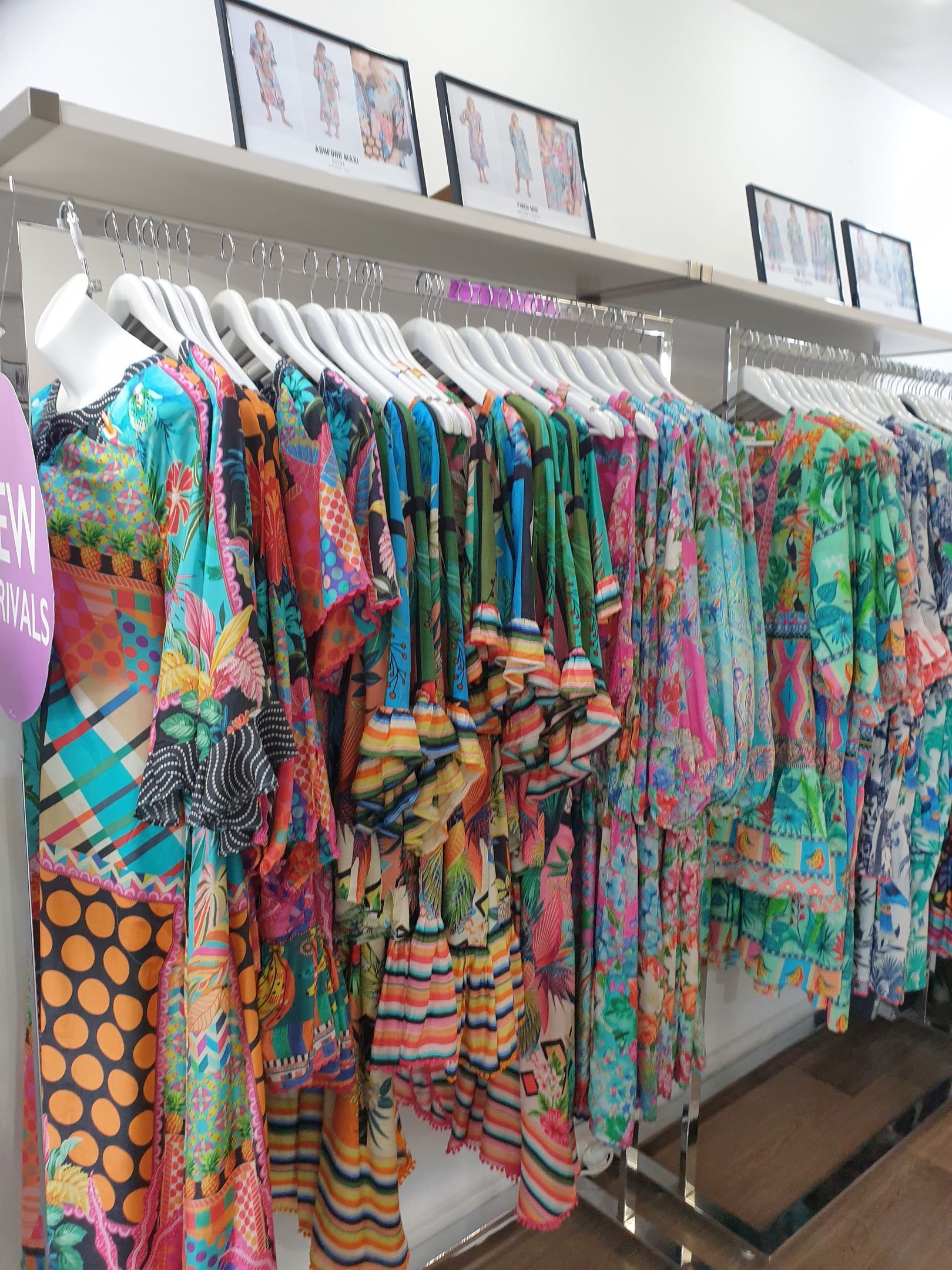 Clothing rack with colorful patterned dresses in a boutique.