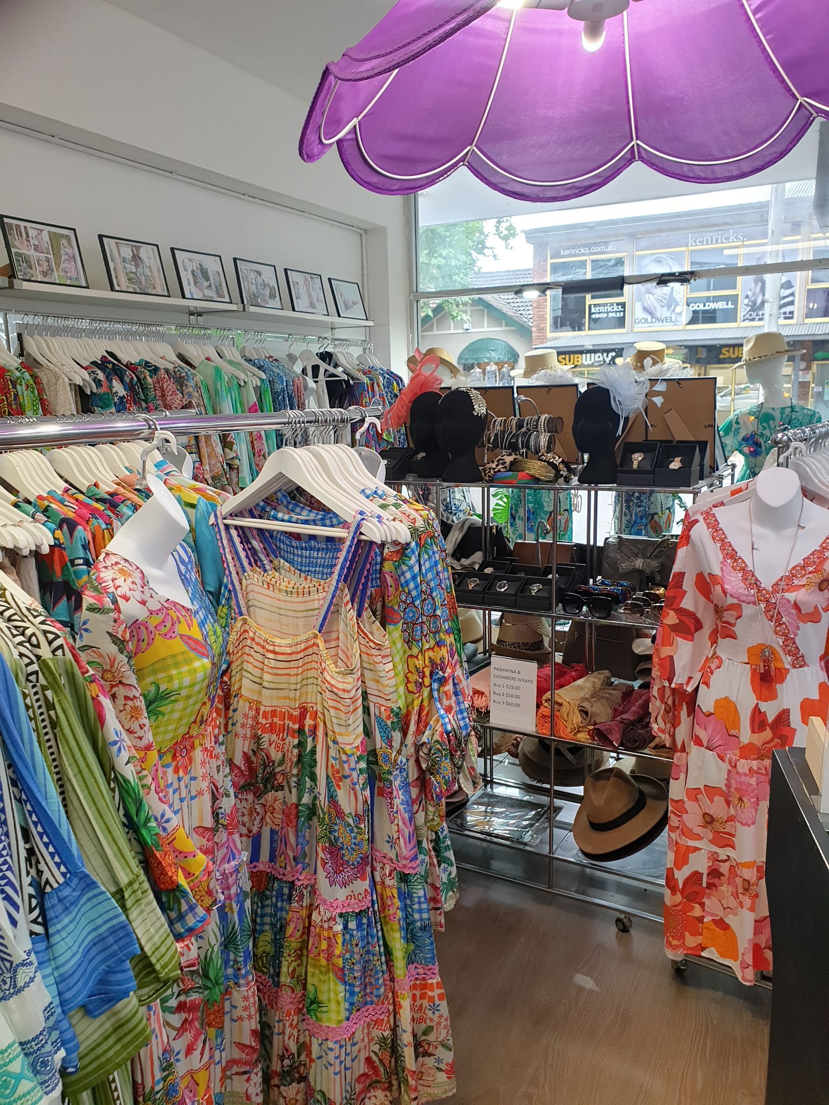 Clothing store interior with racks of colorful dresses and displays of accessories.