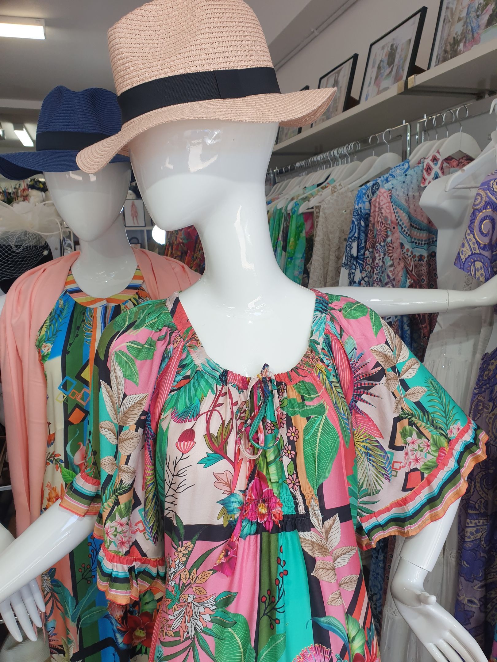 Two mannequins wearing dresses, one floral, in a clothing store.