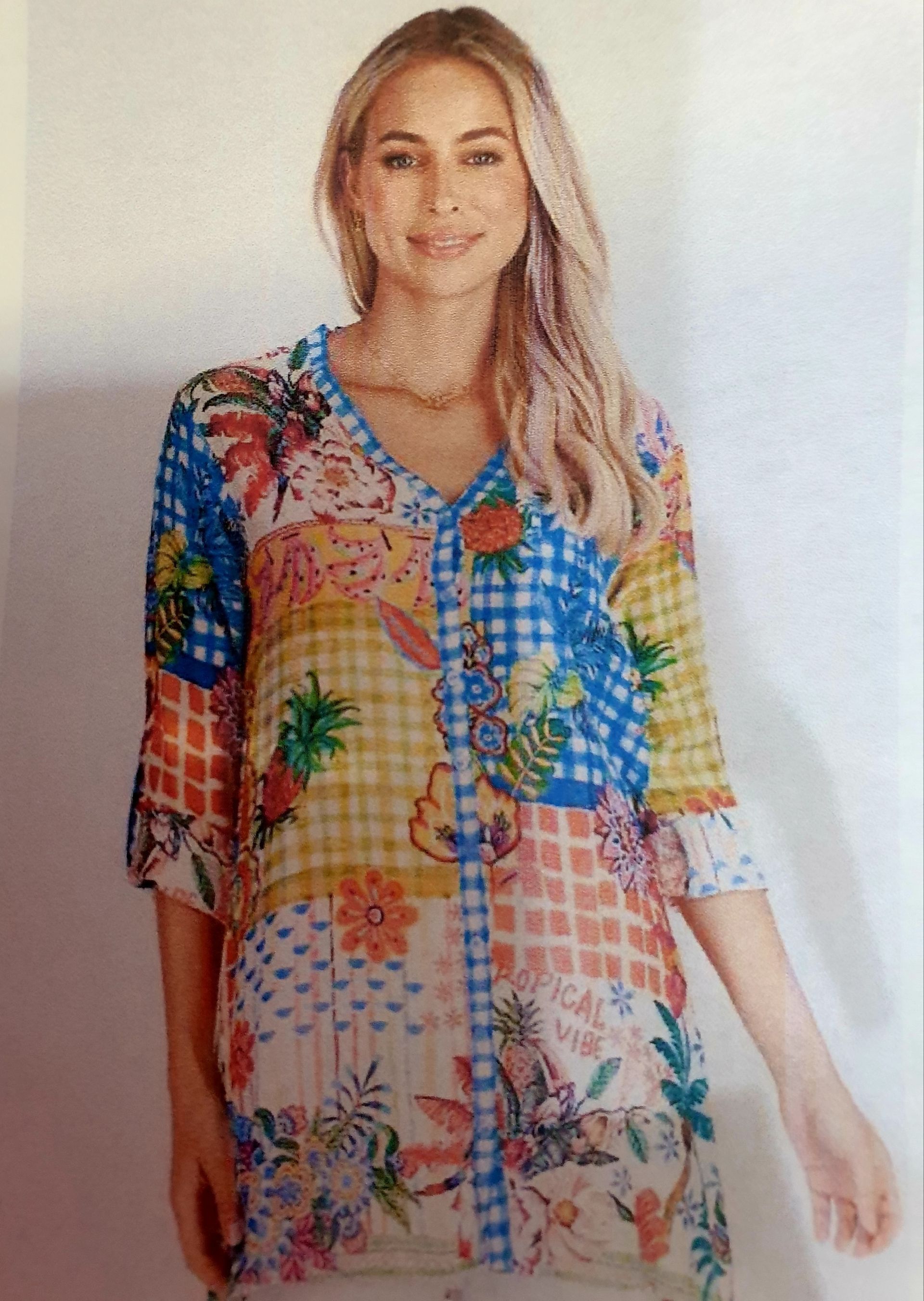 Woman in a patchwork print shirt; floral, plaid, and solid squares in various colors.