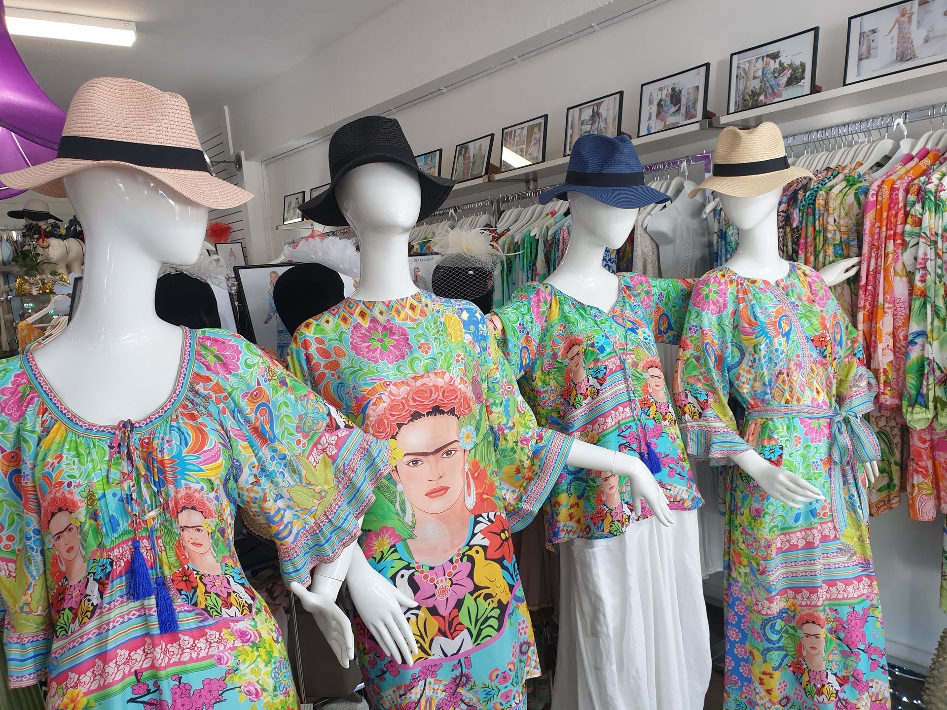 Four mannequins in a clothing store wear colorful floral print tops and hats.
