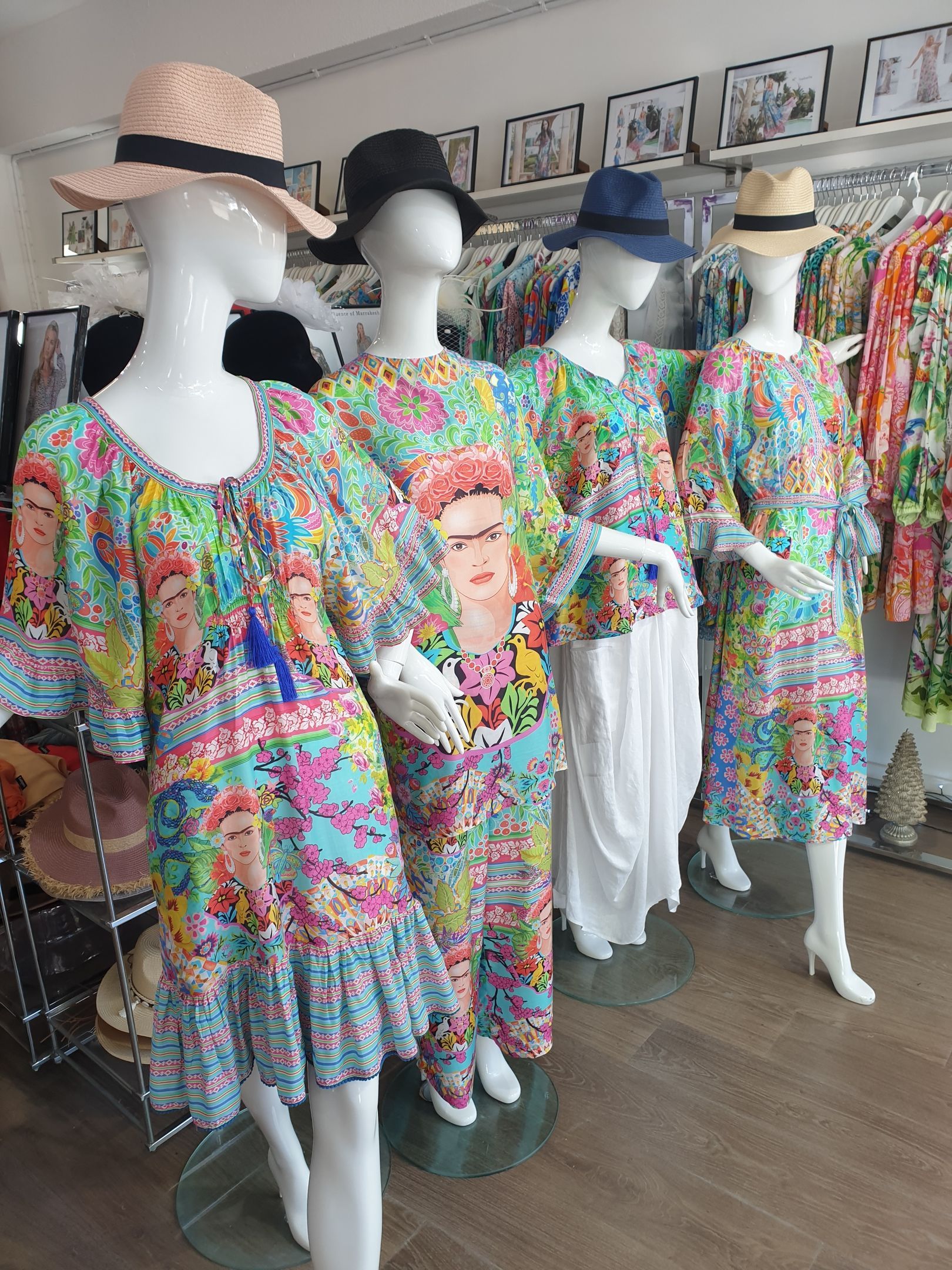 Four mannequins in a shop, wearing Frida Kahlo print dresses and hats.