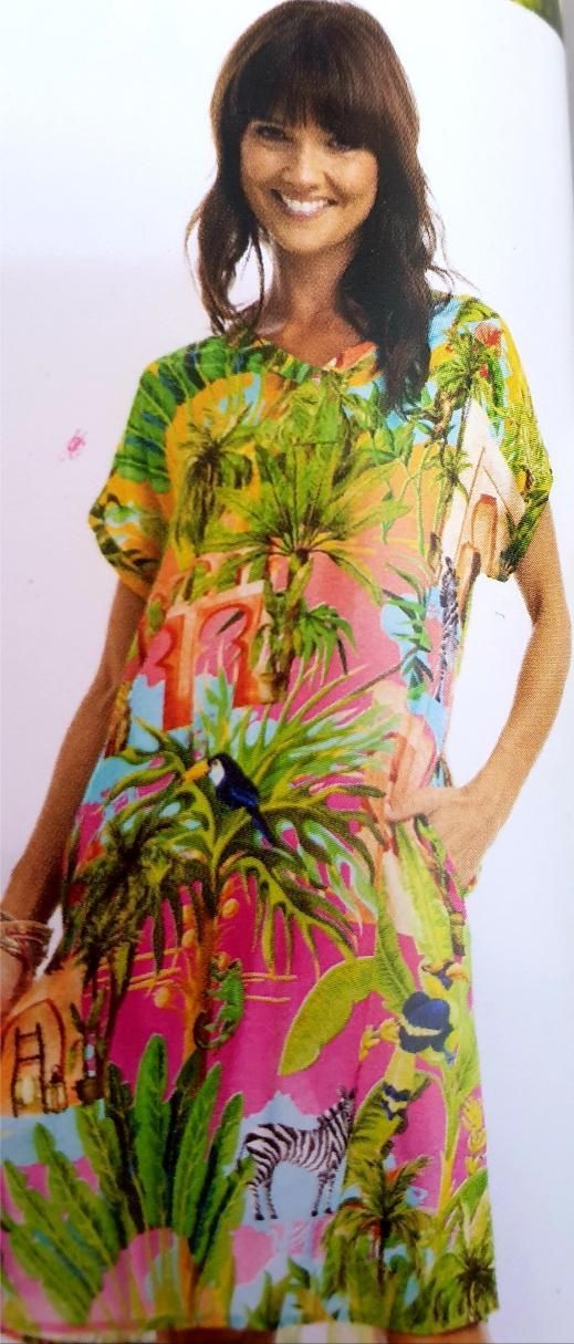 Woman wearing a colorful tropical print dress, smiling.