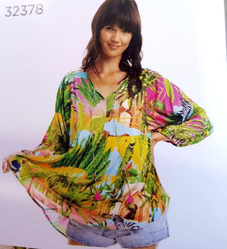 Woman wearing colorful tropical print blouse and denim shorts.