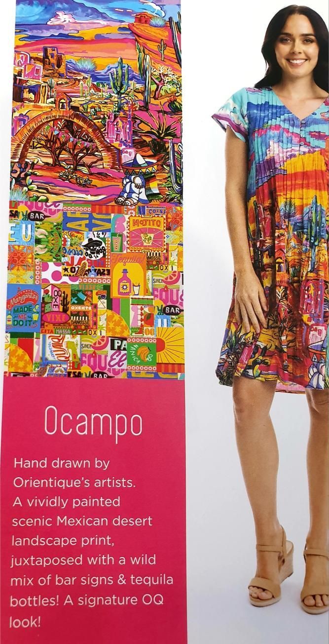 Woman in colorful patterned dress, standing next to a sign about the artist Ocampo.