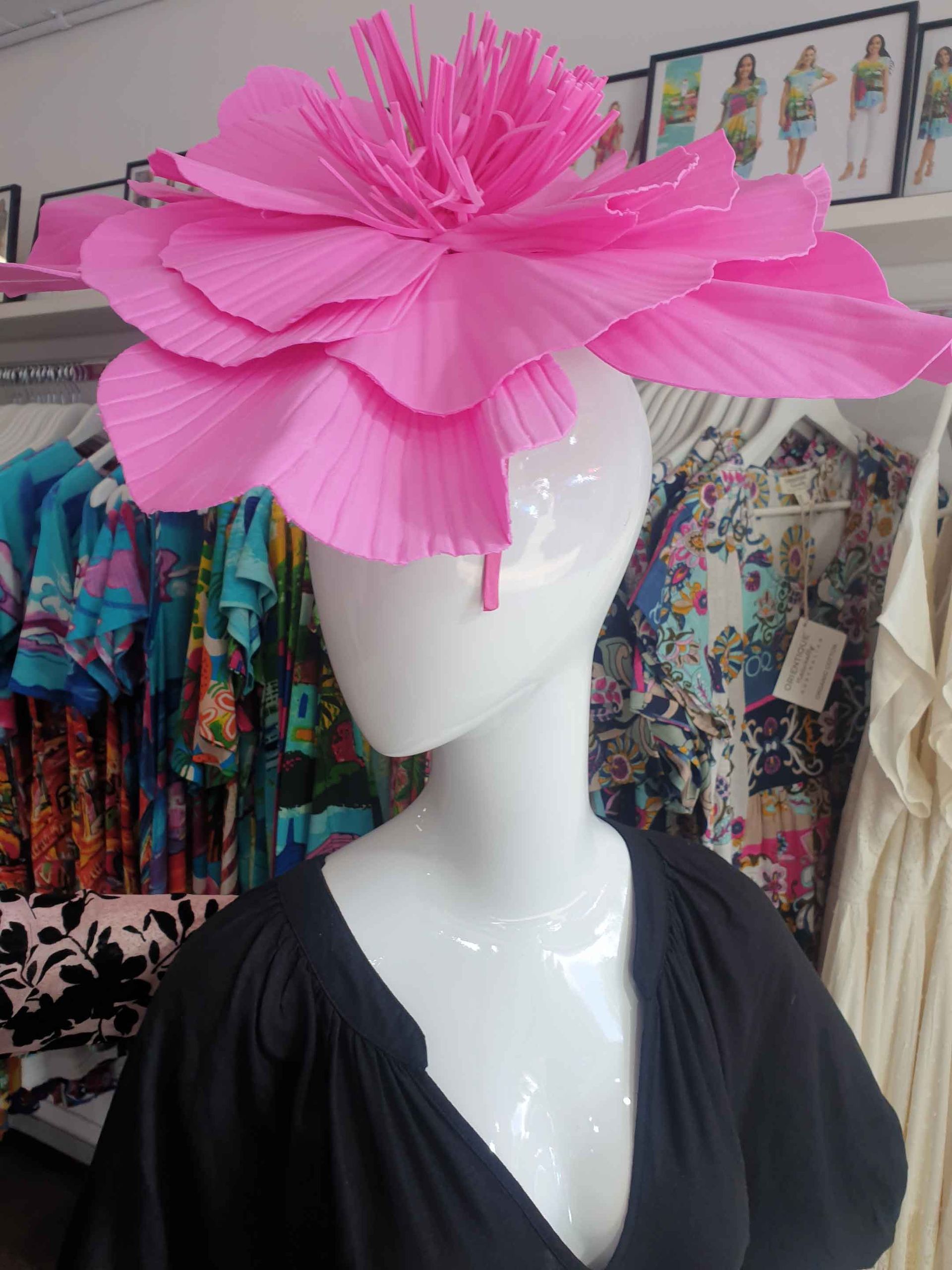 Pink floral hat on a white mannequin head in a clothing store.