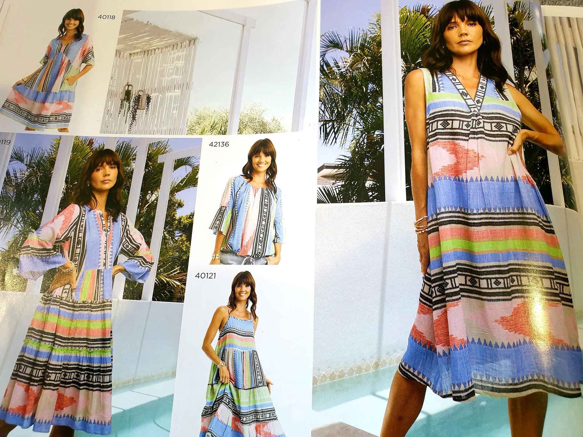 Women modeling colorful patchwork-patterned clothing: dresses and a top. Poolside setting, sunny day.